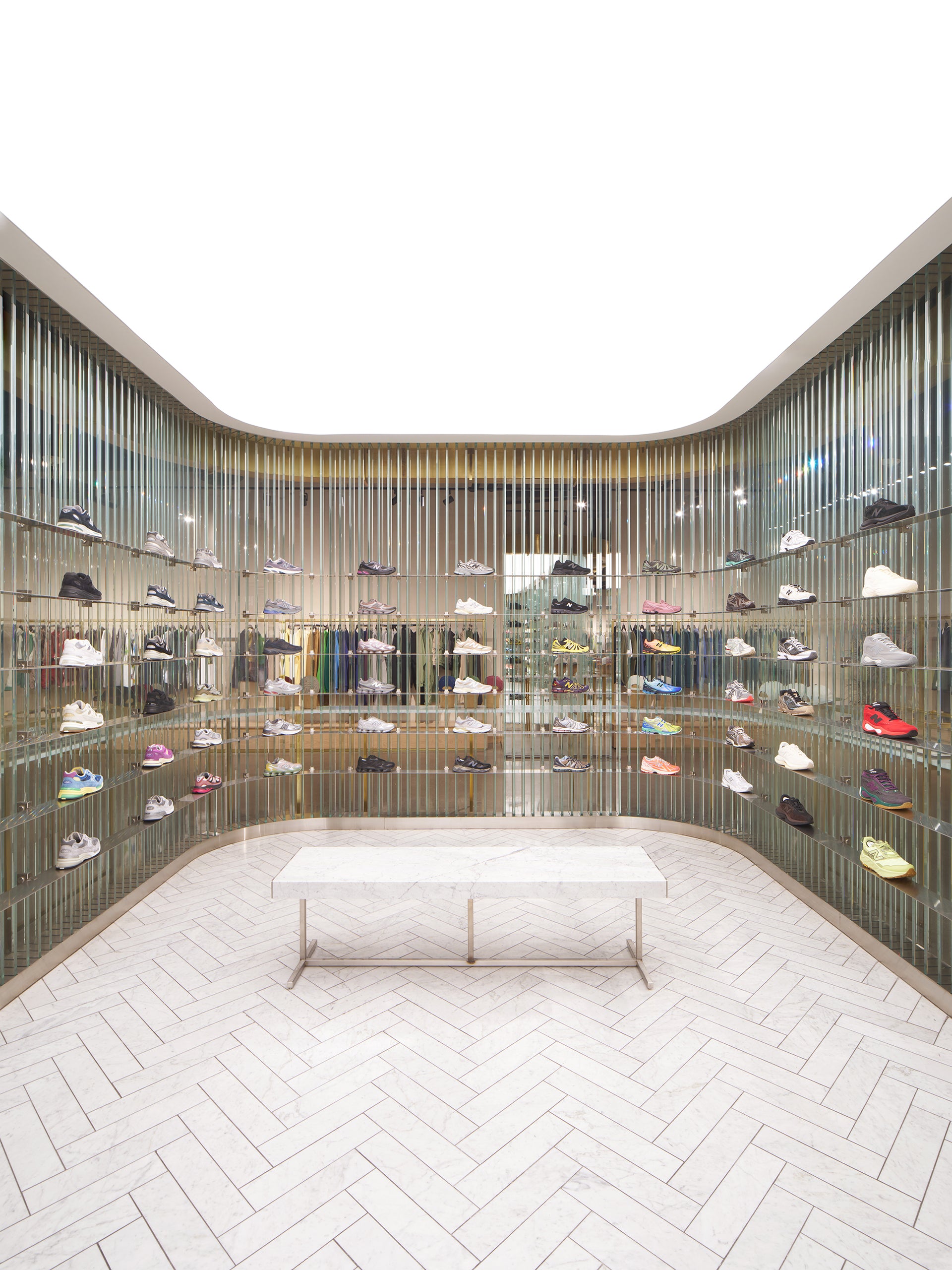 Kith store curved sneaker display wall with glass rods and marble bench, interior view