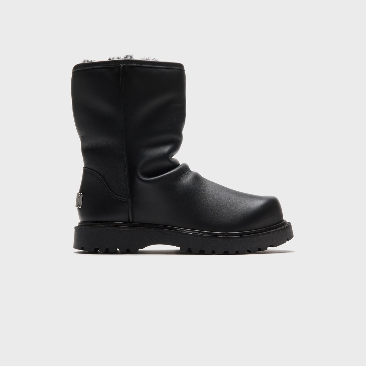 UGG x Willy Chavarria Relaxed Boot in Black leather, lateral side view showing the shearling collar and lugged sole