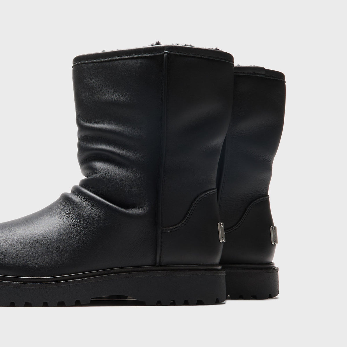 UGG x Willy Chavarria Relaxed Boot in Black leather, close-up of the engraved UGG and Willy Chavarria heel tabs