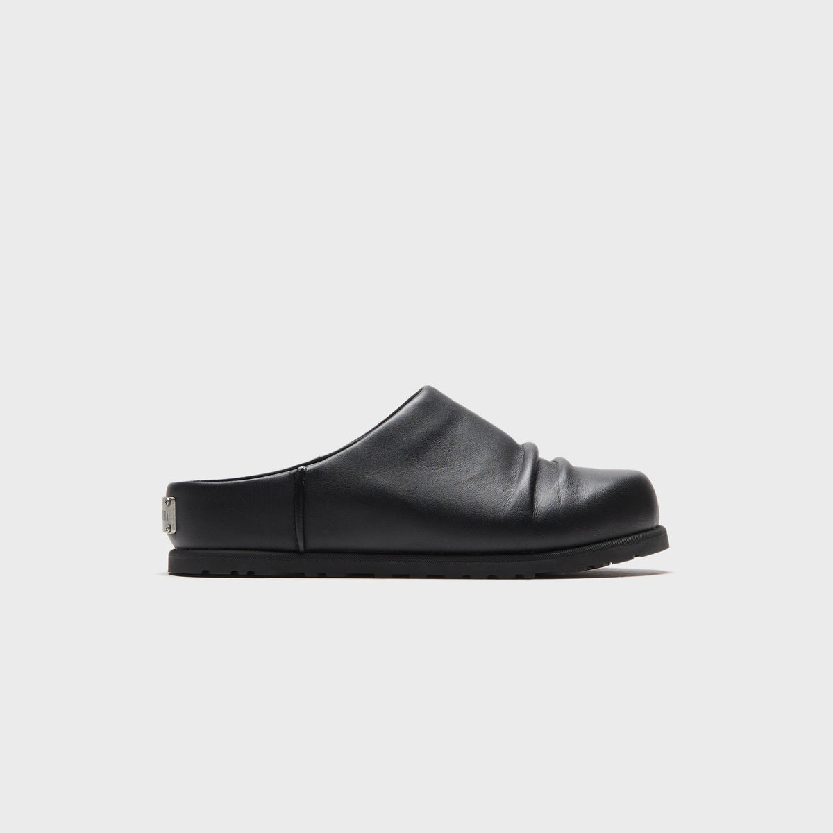 UGG x Willy Chavarria Otzo Clog in Black leather, lateral side view showing the ruched vamp and closed-back mule silhouette