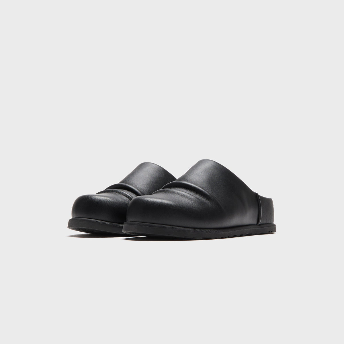 UGG x Willy Chavarria Otzo Clog in Black leather, front three-quarter view of the pair on a lugged outsole