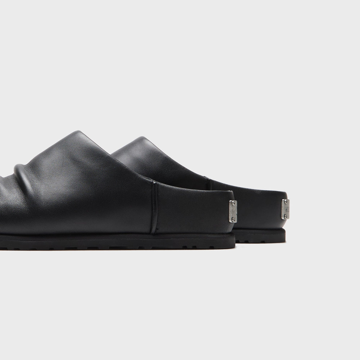UGG x Willy Chavarria Otzo Clog in Black leather, close-up of the engraved UGG and Willy Chavarria metal heel tabs