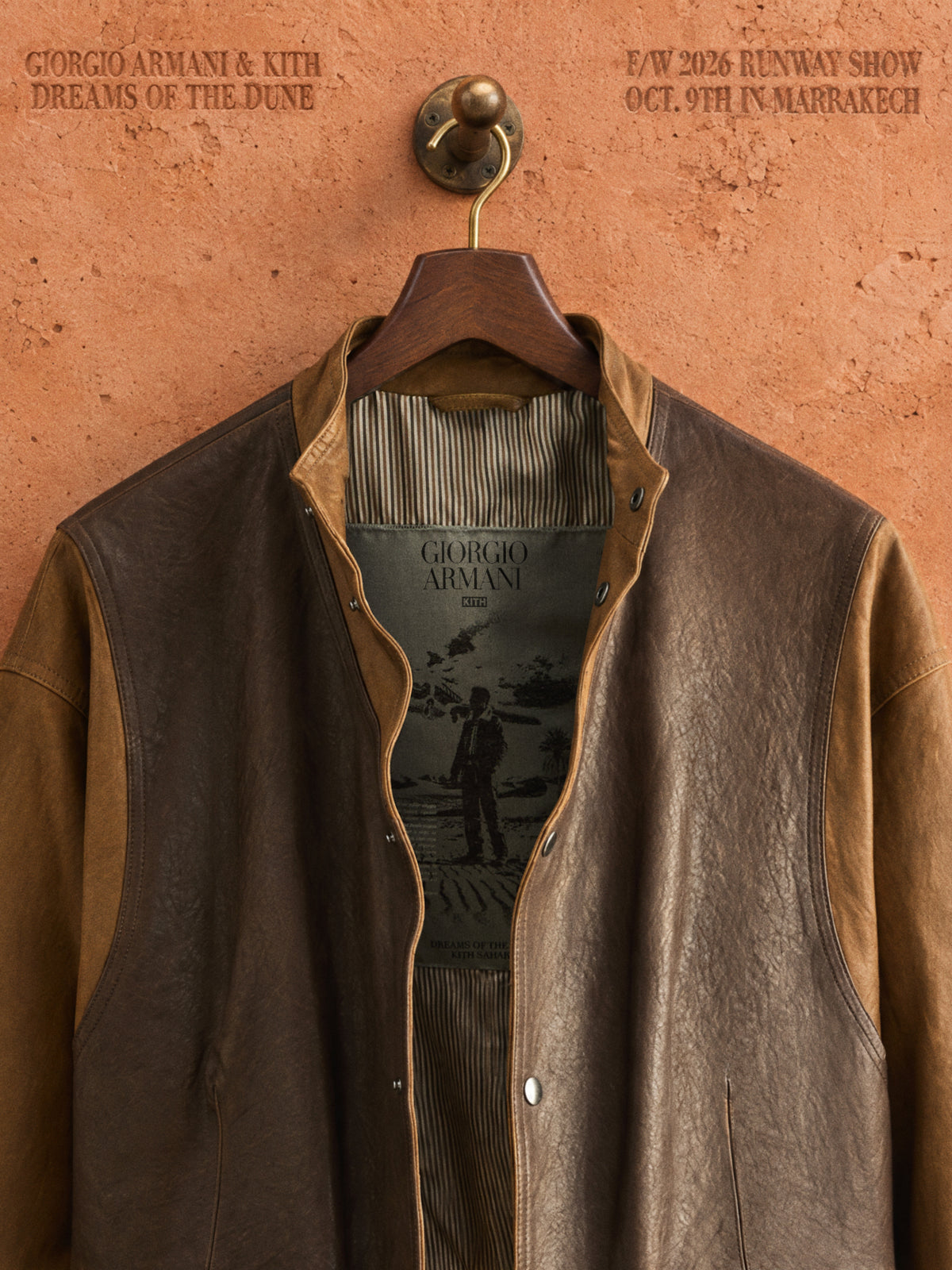 Giorgio Armani x Kith brown and tan leather bomber jacket on wooden hanger against terracotta wall, Dreams of the Dune F/W 2026