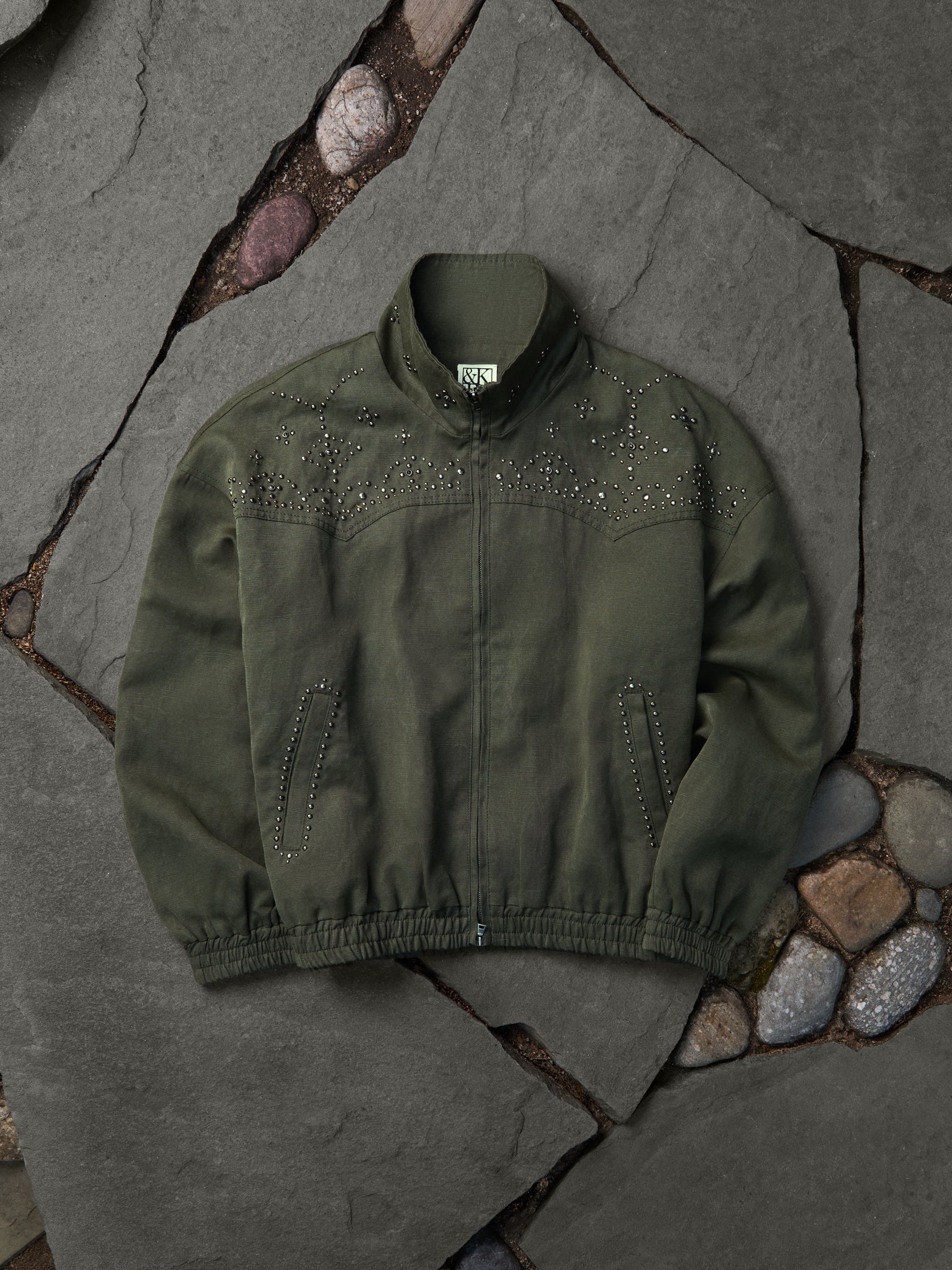 Olive rhinestone-studded western bomber jacket, flat-lay front view on grey flagstone