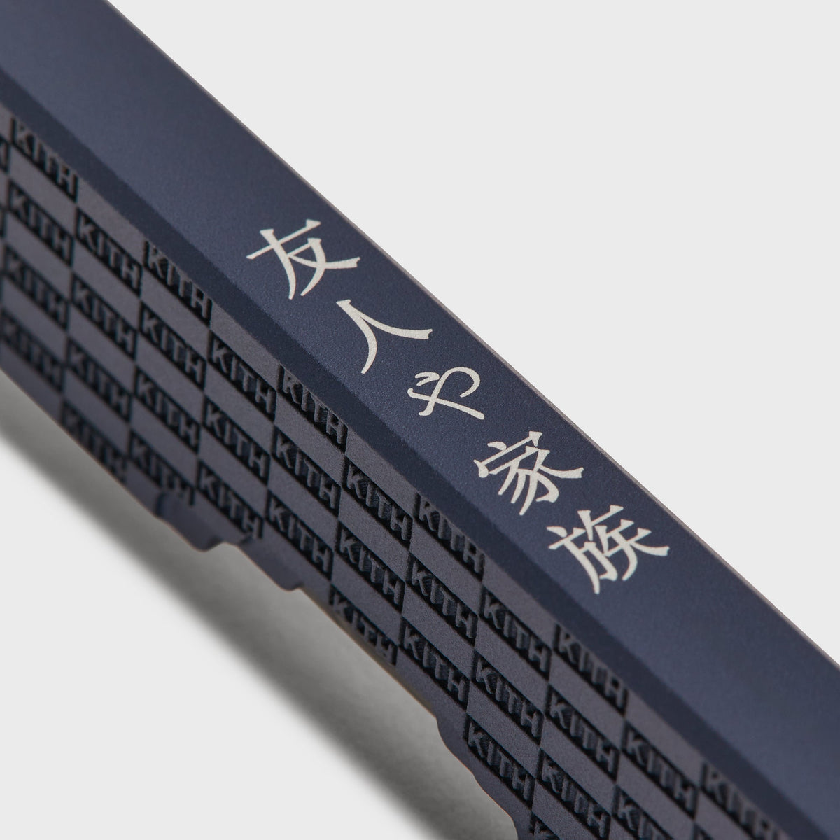 Close-up of the knife spine engraved with Japanese characters and the KITH checkerboard pattern, navy Nocturnal colorway