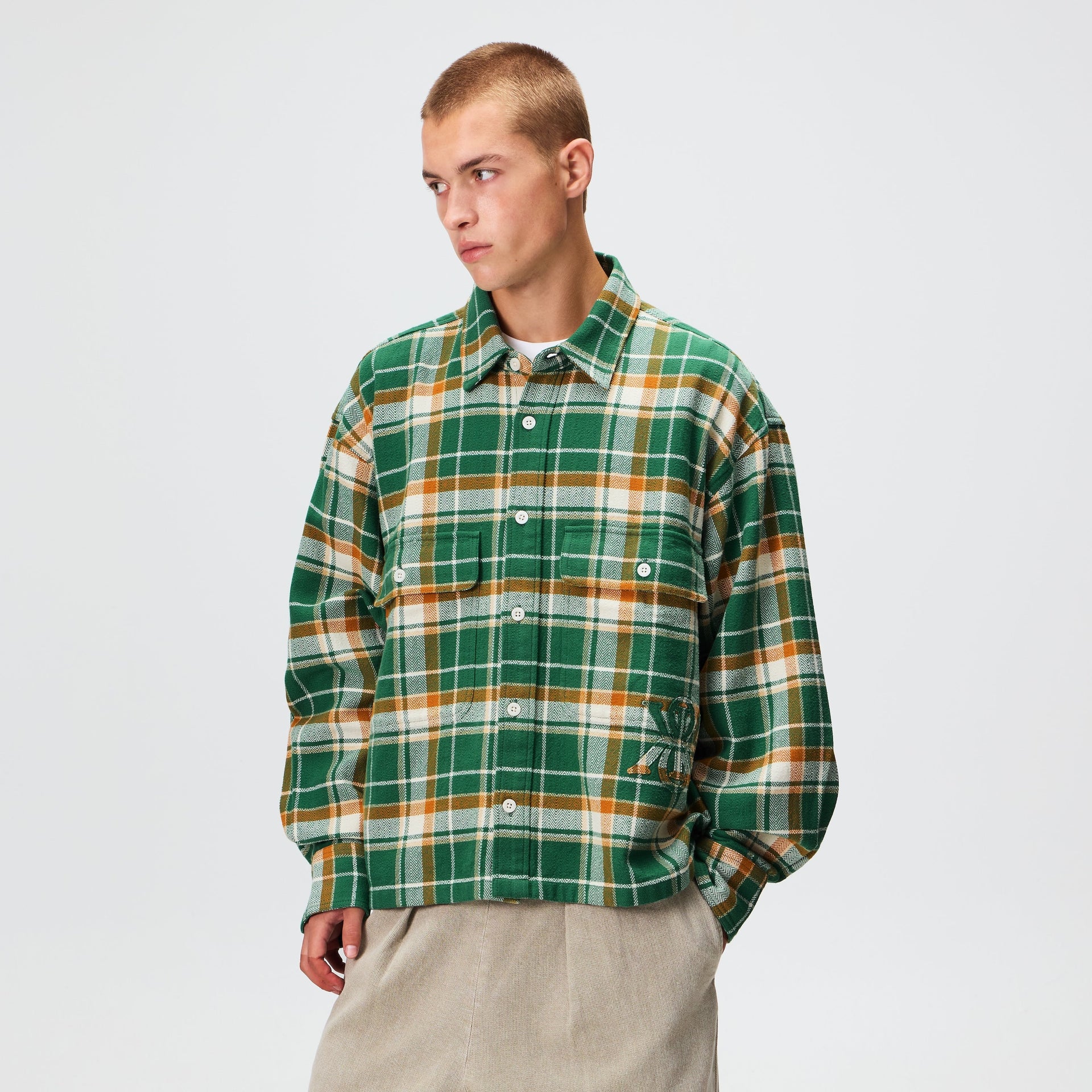 Man wearing the Kith Plaid Henson buttondown shirt in alpine plaid flannel with khaki shorts