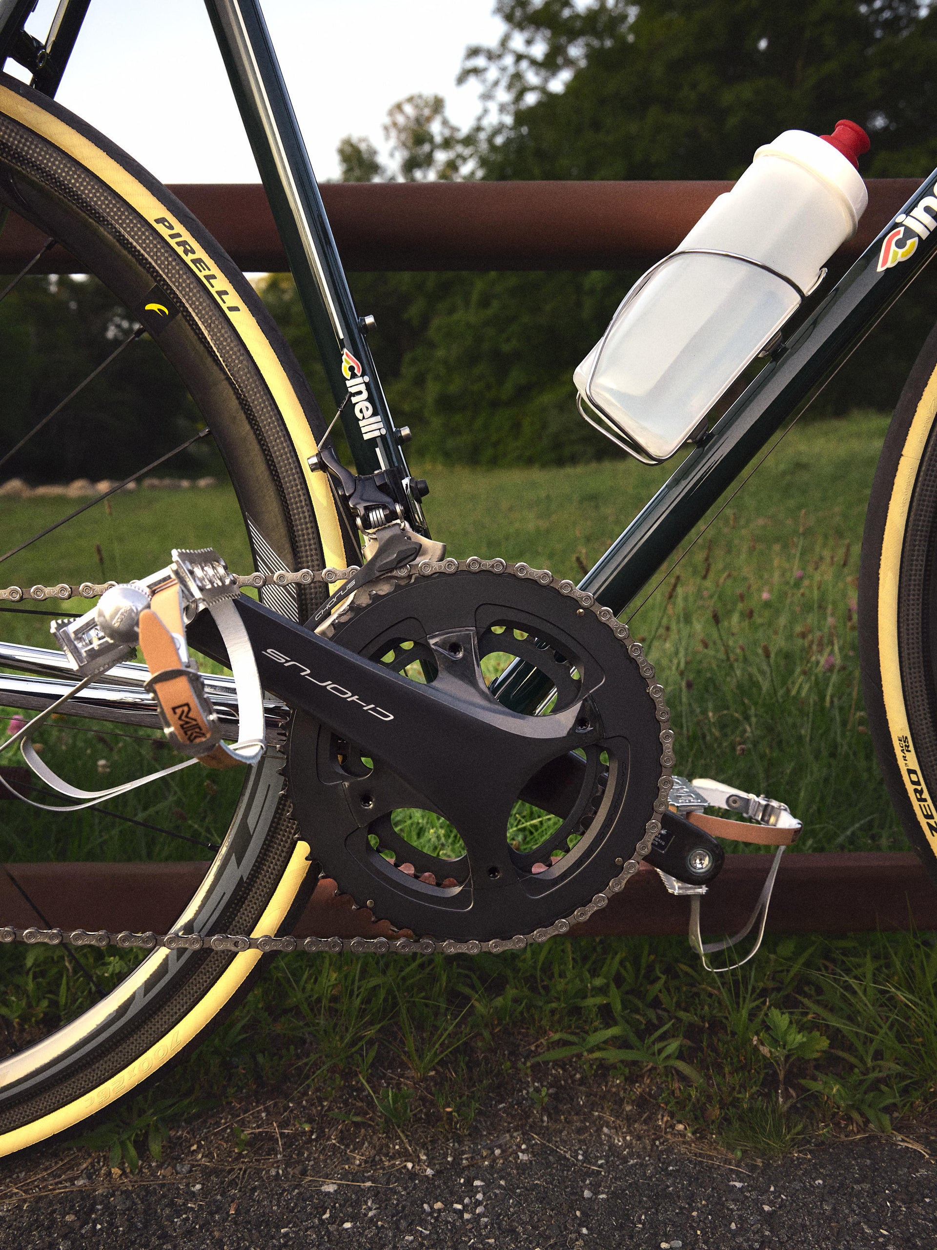 Detail of green Cinelli road bike drivetrain: Campagnolo Chorus crankset, Pirelli tire and white bottle, side view