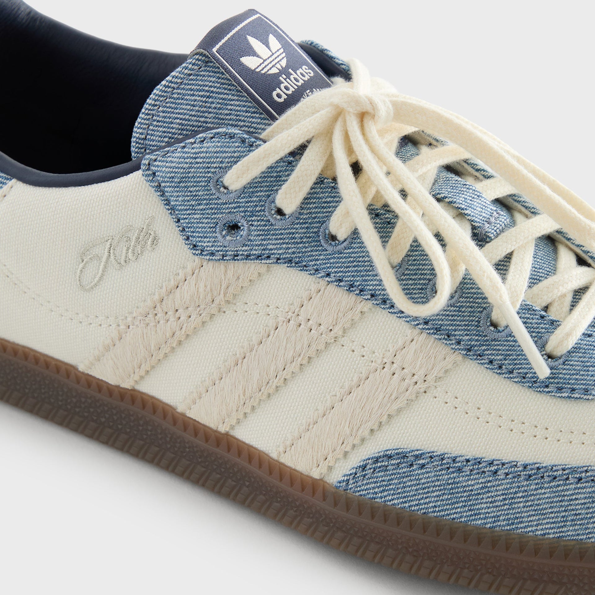 Macro detail of the three stripes, Kith script logo, and adidas tongue tab on the Samba "Denim" sneaker