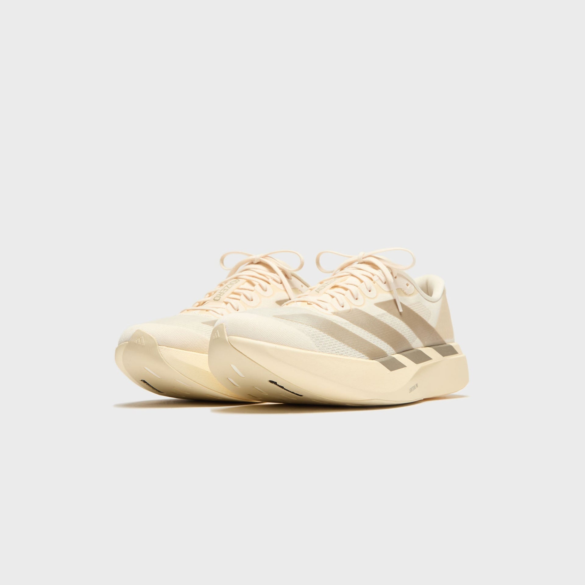 adidas Adizero Evo SL sneakers in Wonder White with tan stripes, front three-quarter view at Kith