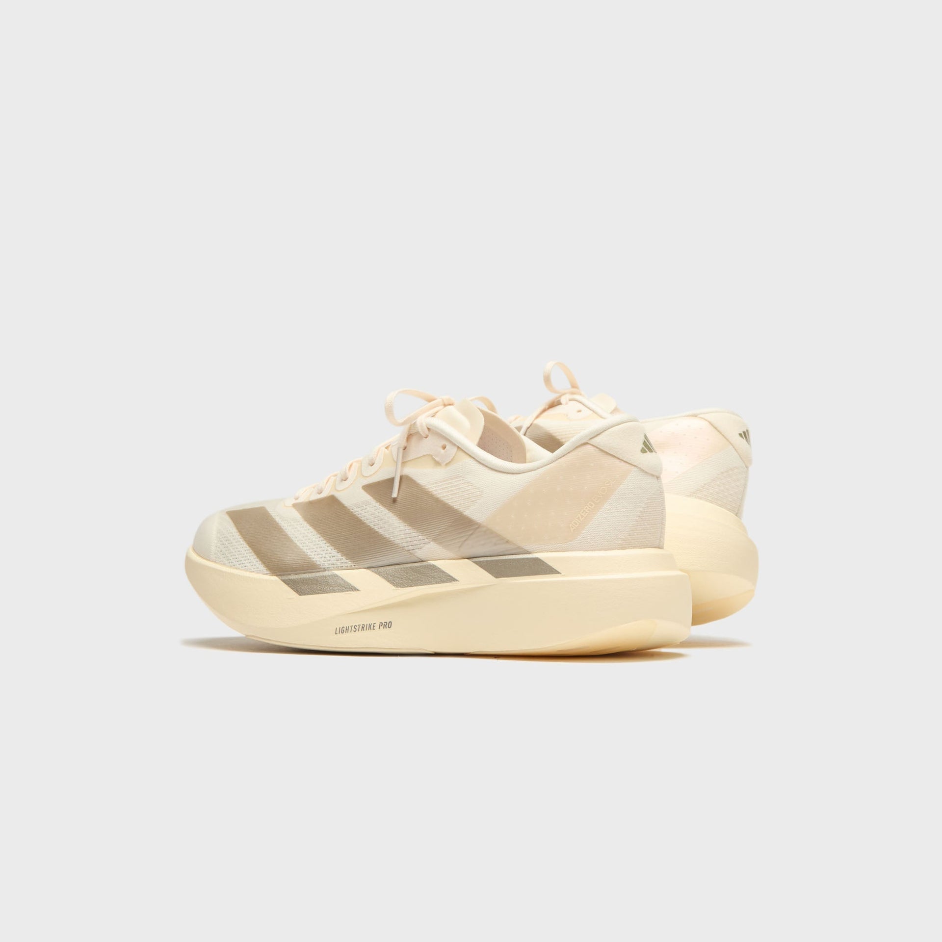 adidas Adizero Evo SL running shoes in Wonder White with tan stripes, rear angle view at Kith