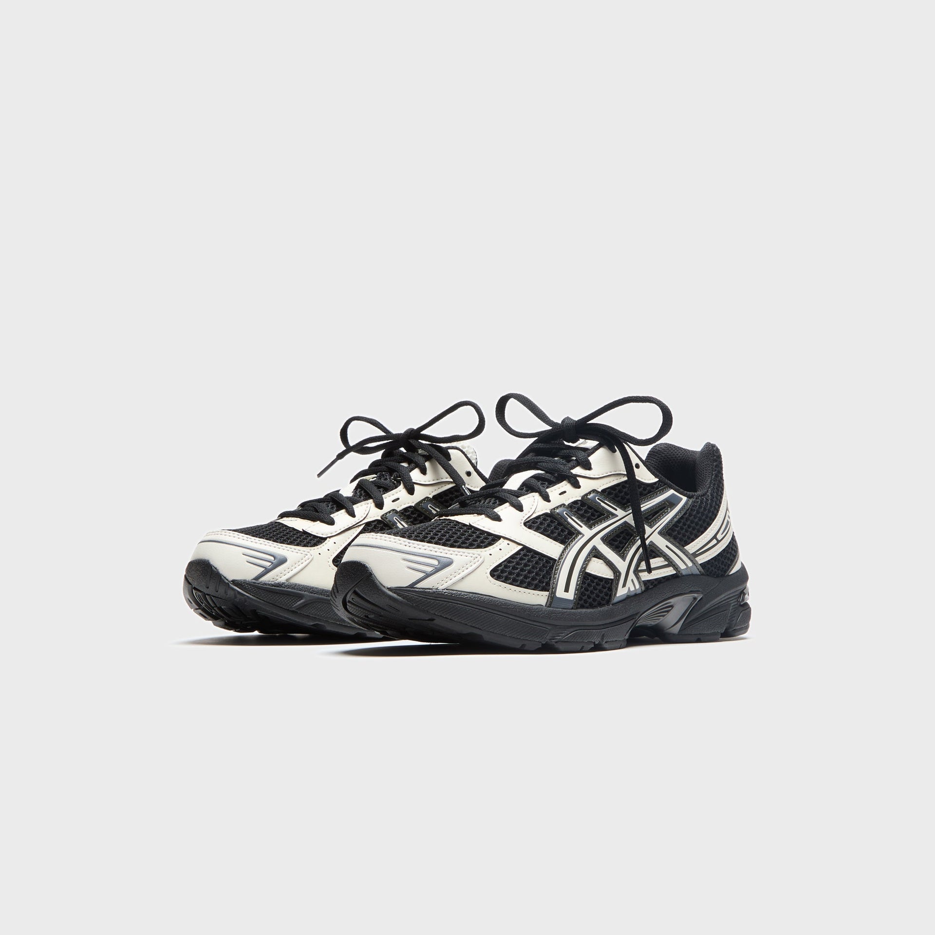 ASICS GEL-1130 sneakers in black and cream with silver, front three-quarter view at Kith