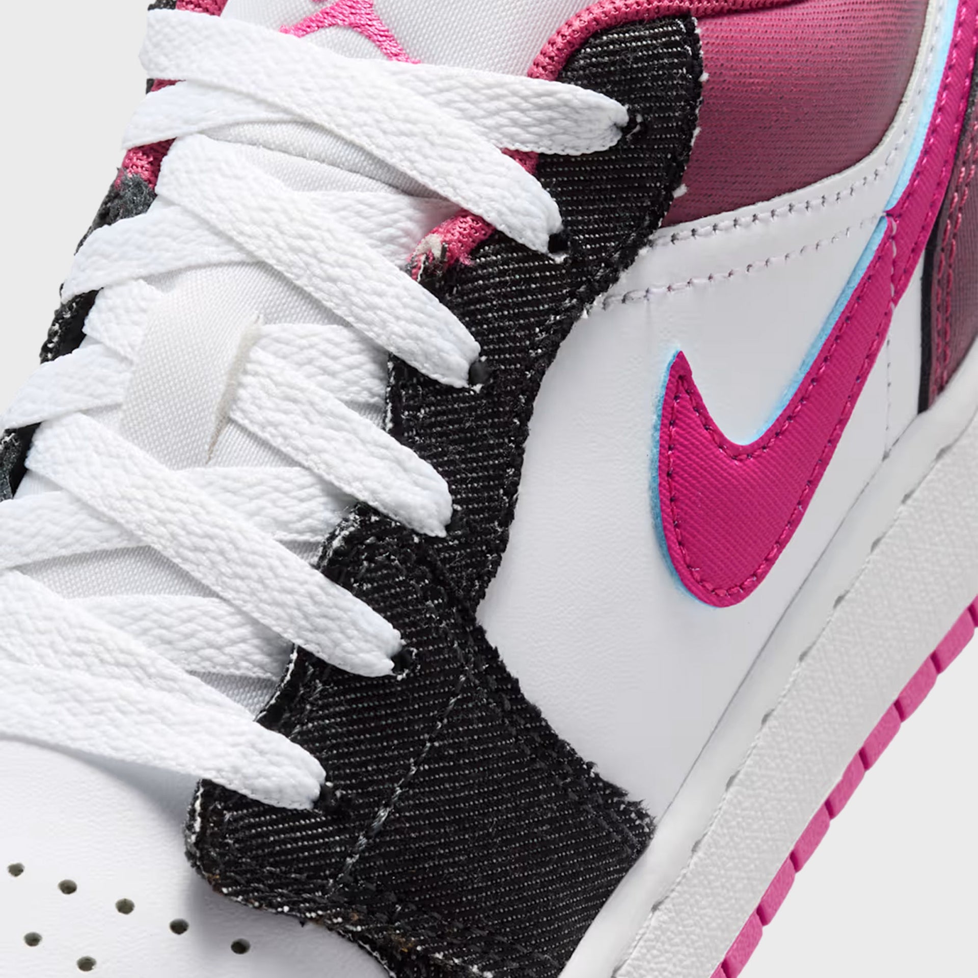 GS Air Jordan 1 Low SE detail of distressed black denim overlay, white laces and blue-outlined fuchsia Swoosh