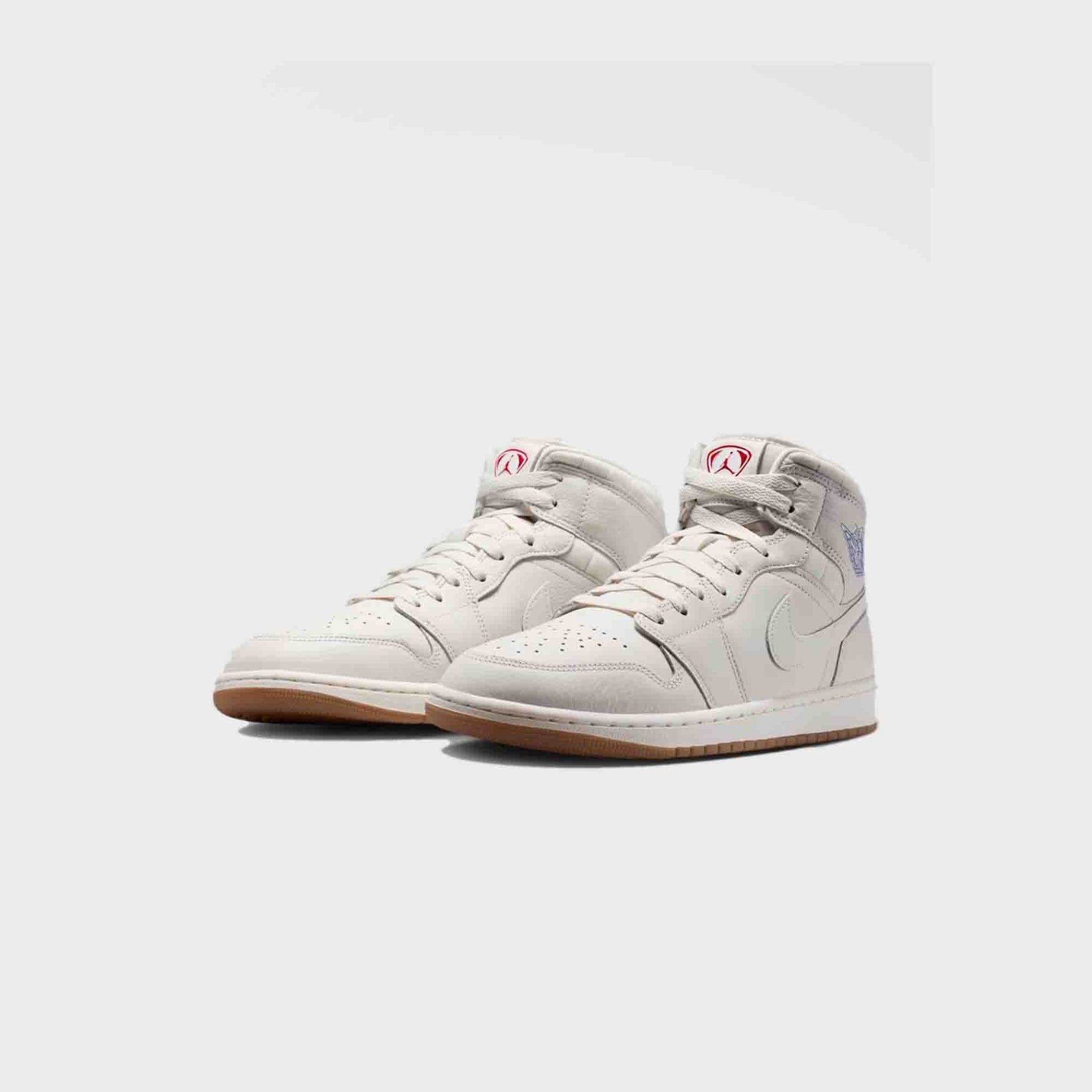 Air Jordan 1 Mid SE pair, front three-quarter view showing red Jumpman tongue tags and a blue ankle graphic