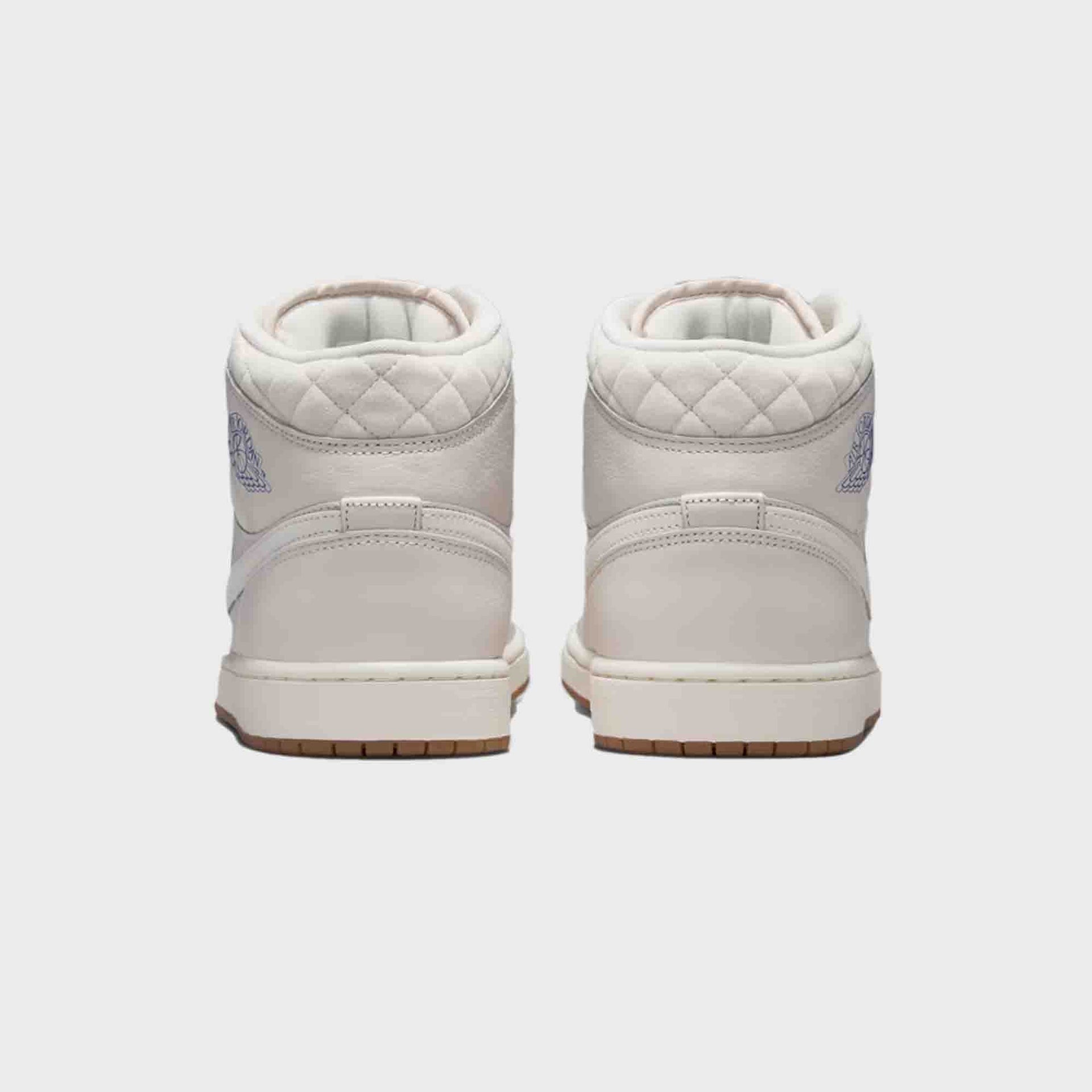 Air Jordan 1 Mid SE pair, heel view with quilted collars and blue Wings logos above gum soles