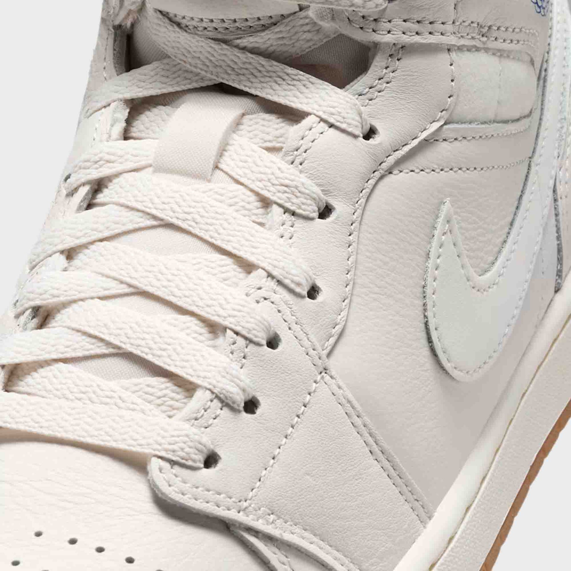 Air Jordan 1 Mid SE close-up of tumbled Phantom leather toe, laces and Swoosh with blue accents
