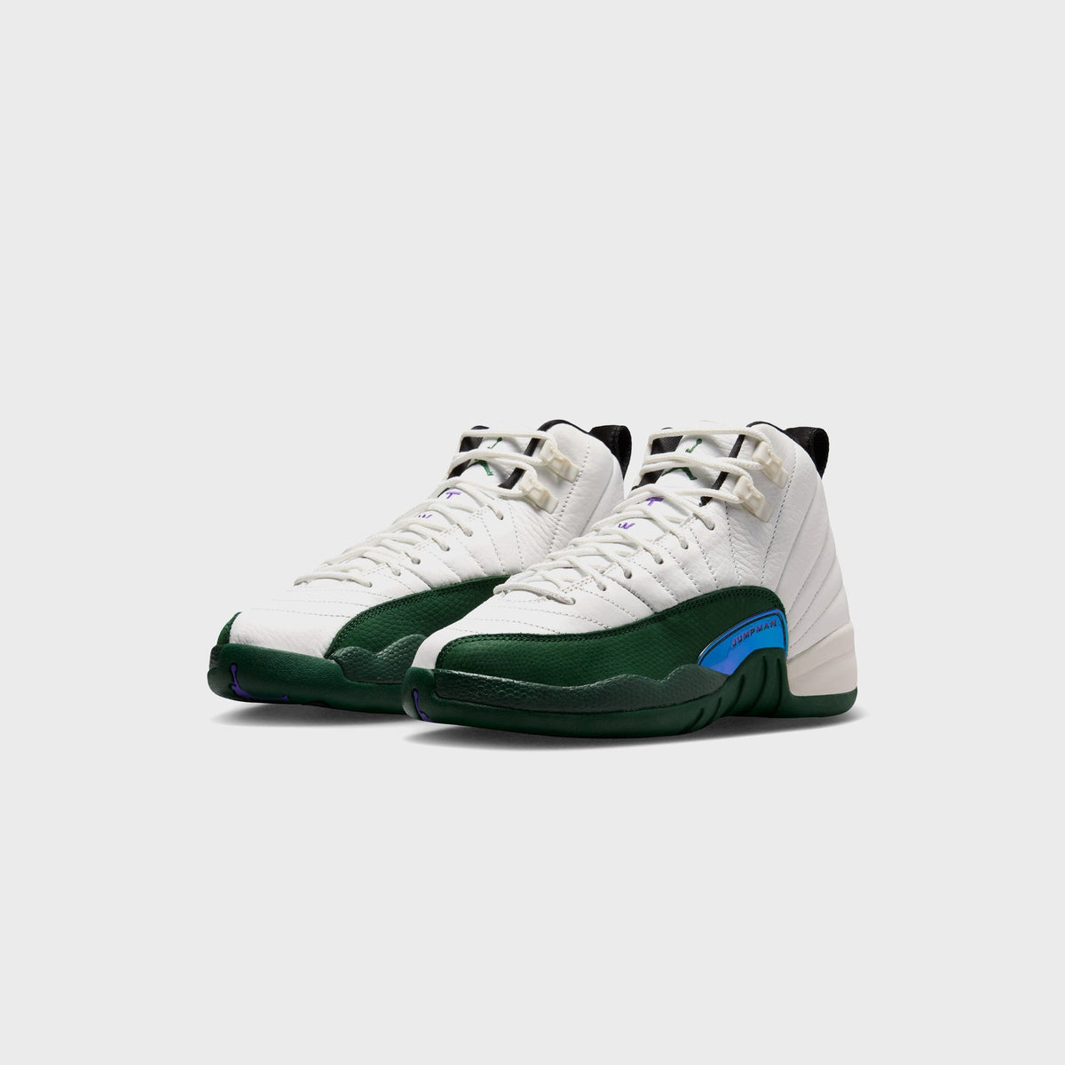 Pair of Jordan GS Air Jordan 12 Retro sneakers in white and green, angled front view showing blue Jumpman mudguard tag