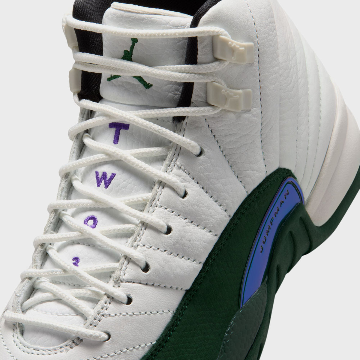 Close-up of Jordan GS Air Jordan 12 Retro lace eyelets showing green Jordan Wings embroidery on white ribbed leather