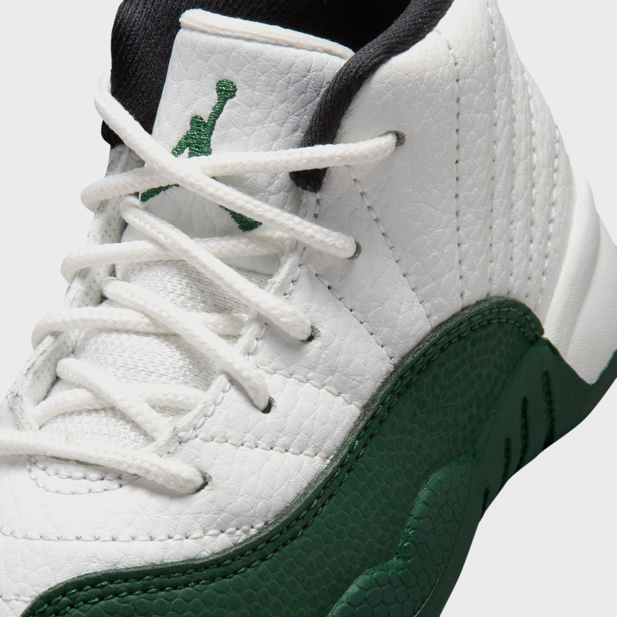 Close-up of Jordan TD Air Jordan 12 Retro toddler pair showing green Jordan Wings embroidery on white ribbed leather