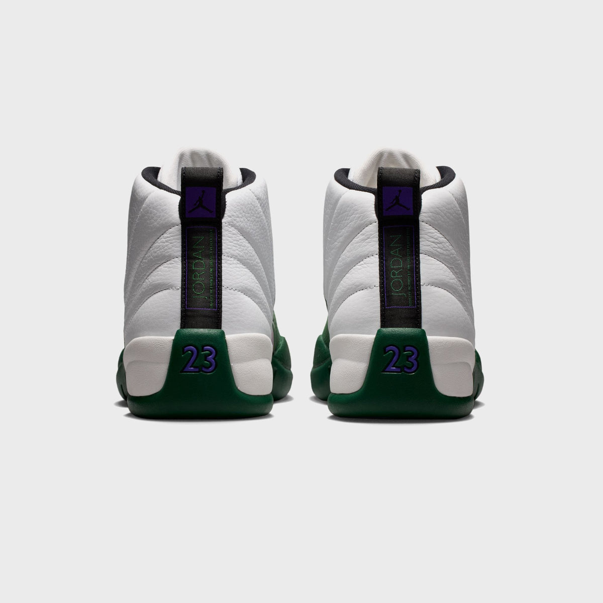Heel view of Air Jordan 12 Retro pair with Jumpman pull tab, purple 23 numbering, and green heel counter