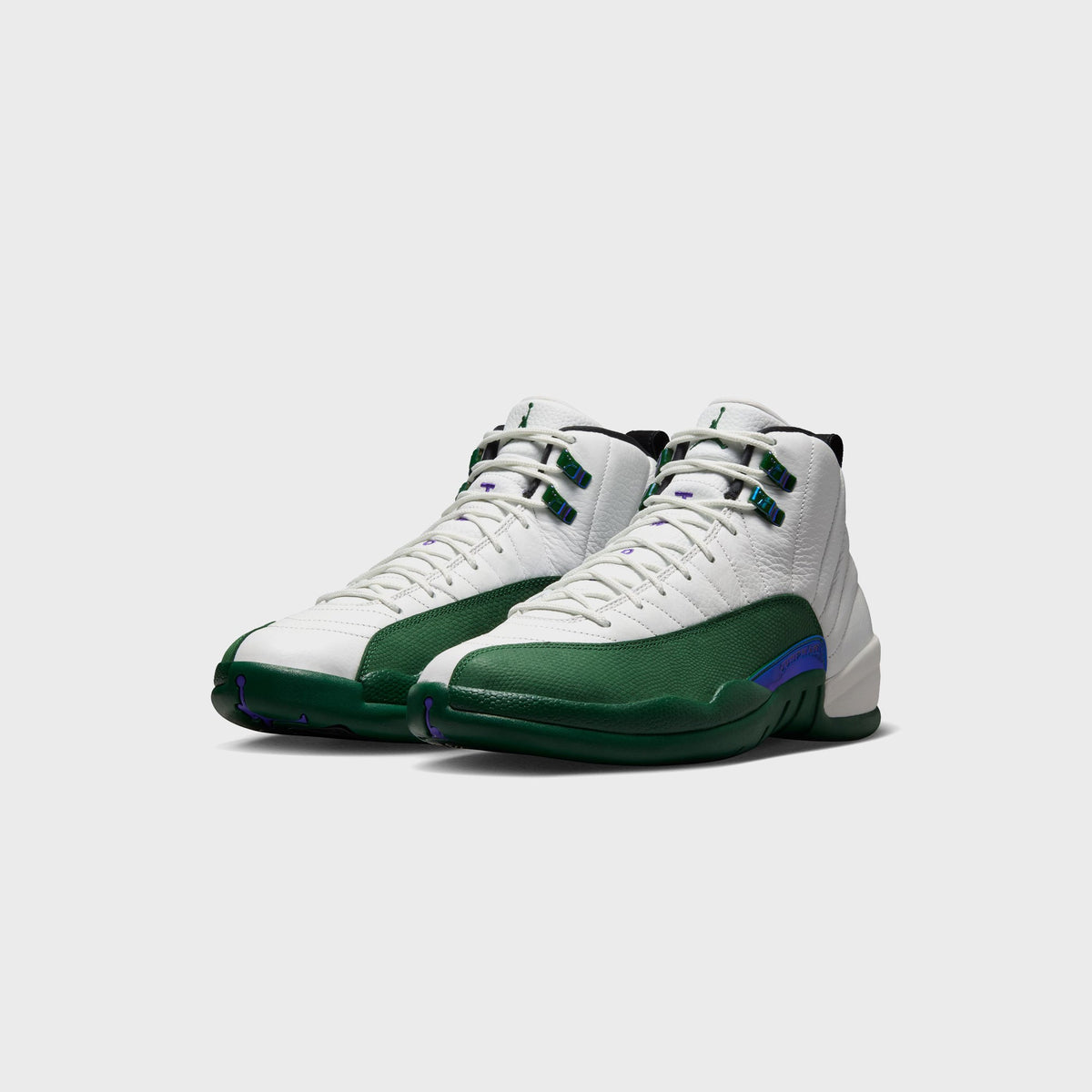 Pair of Air Jordan 12 Retro sneakers in white and green, angled front view showing Fierce Purple Jumbman lace lock