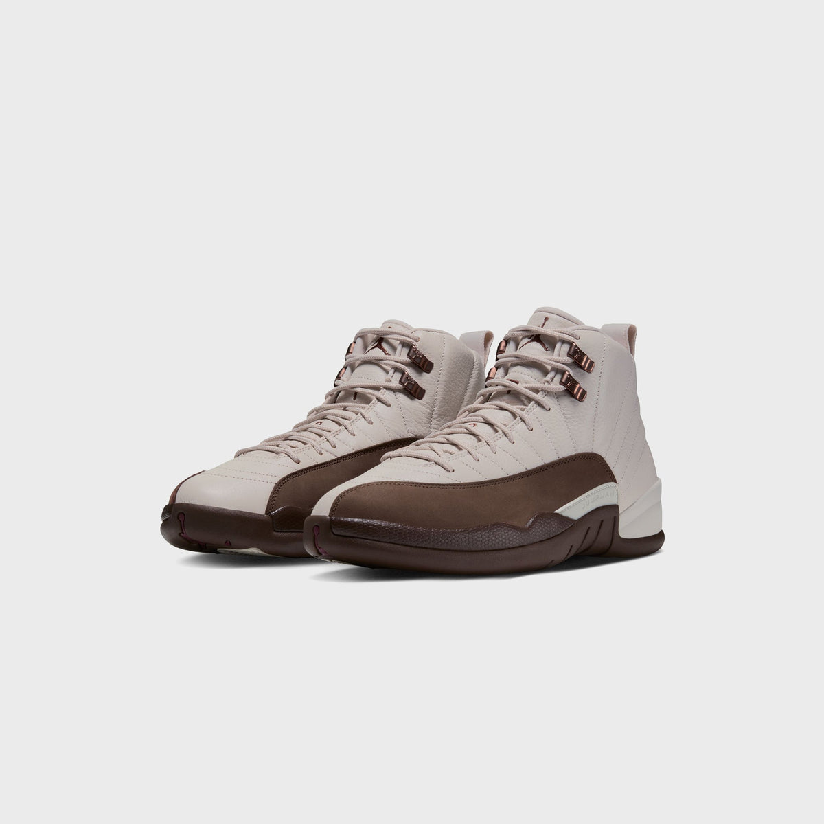 Angled front view of a pair of Air Jordan 12 Retro in Light Orewood Brown, cream leather with Cacao Wow brown suede and sole