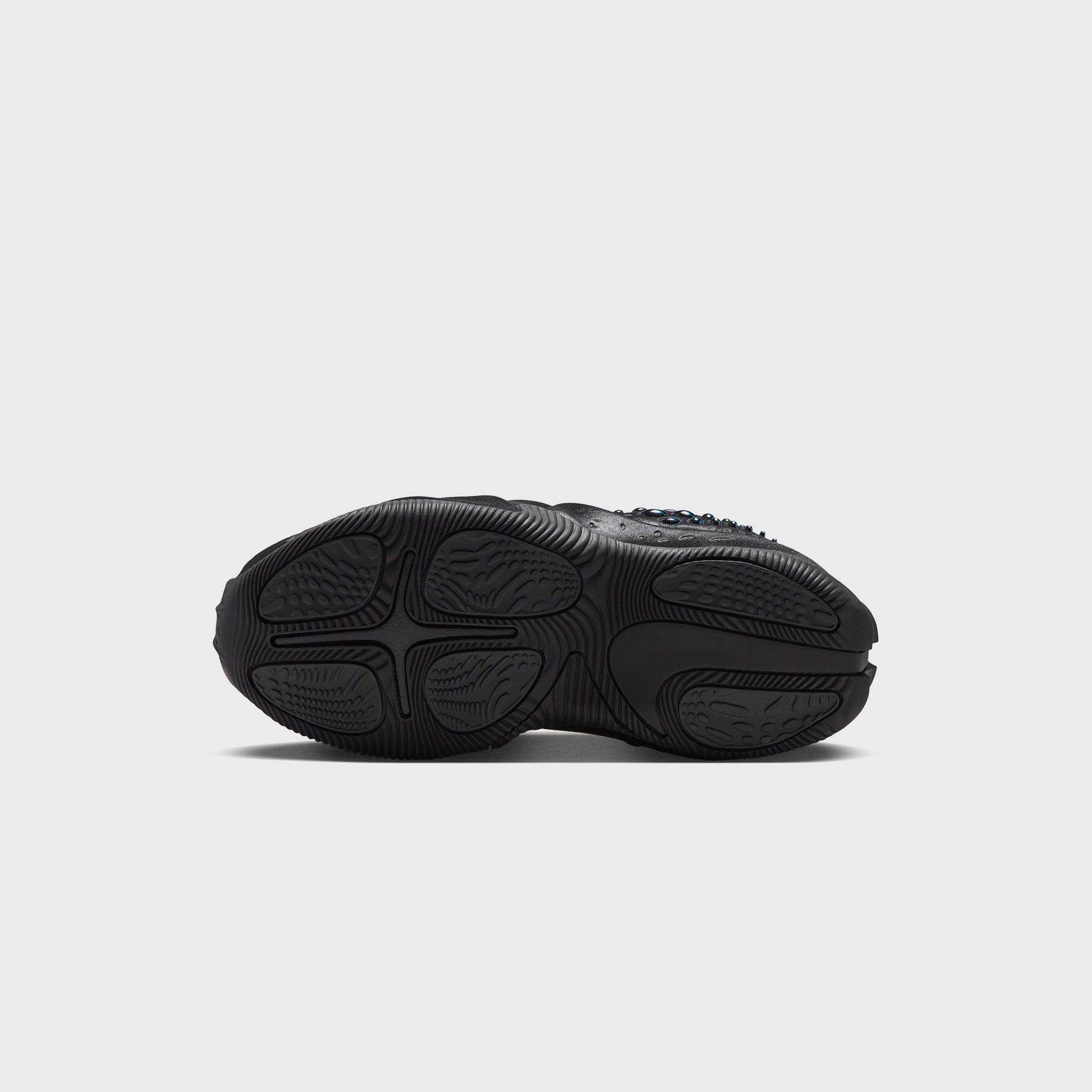 Nike WMNS First Sight Shadow Triple Black, bottom outsole view with cross-shaped flex grooves and textured black traction pods