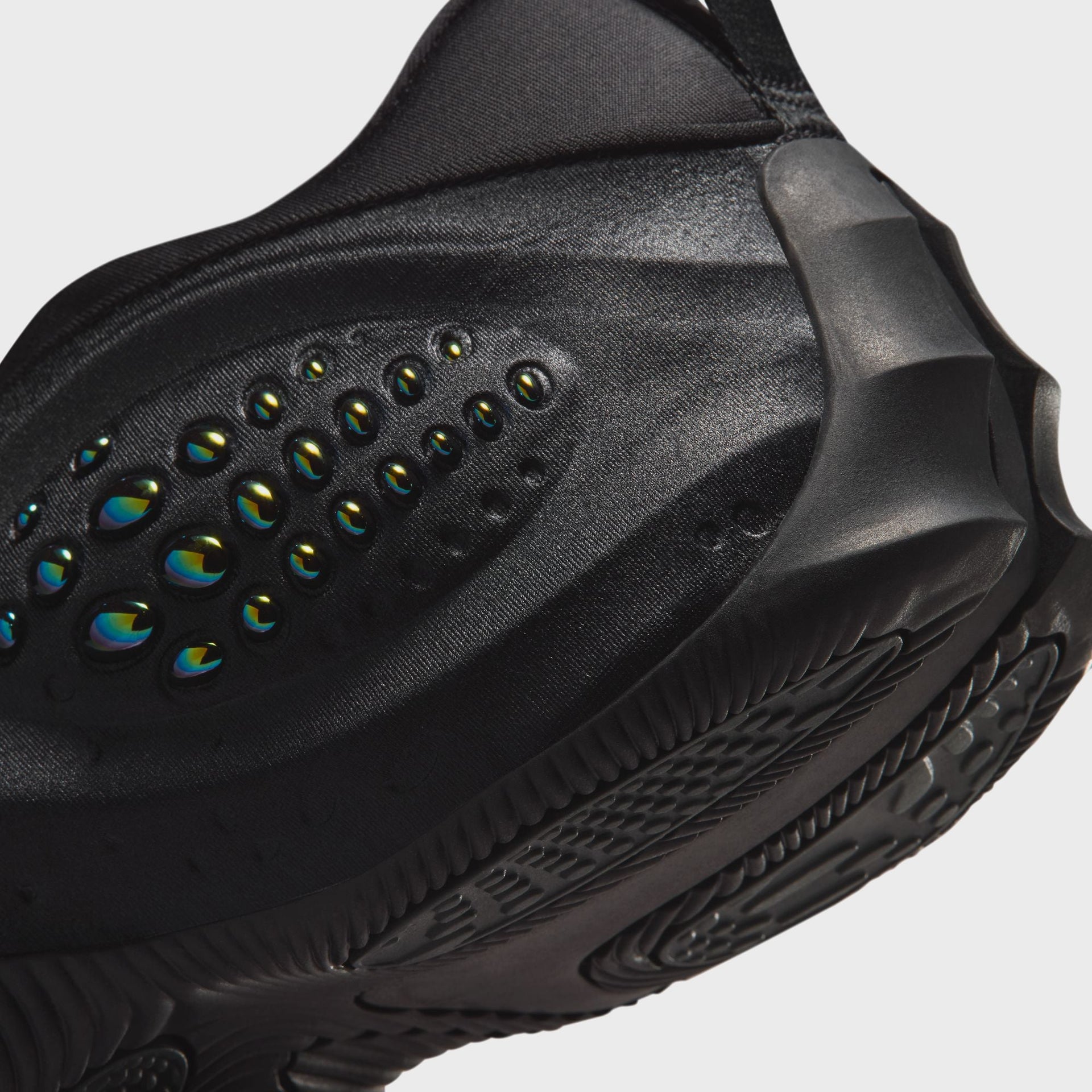Nike WMNS First Sight Shadow Triple Black, macro of the iridescent green-and-blue domed bubble pod on the glossy black shell