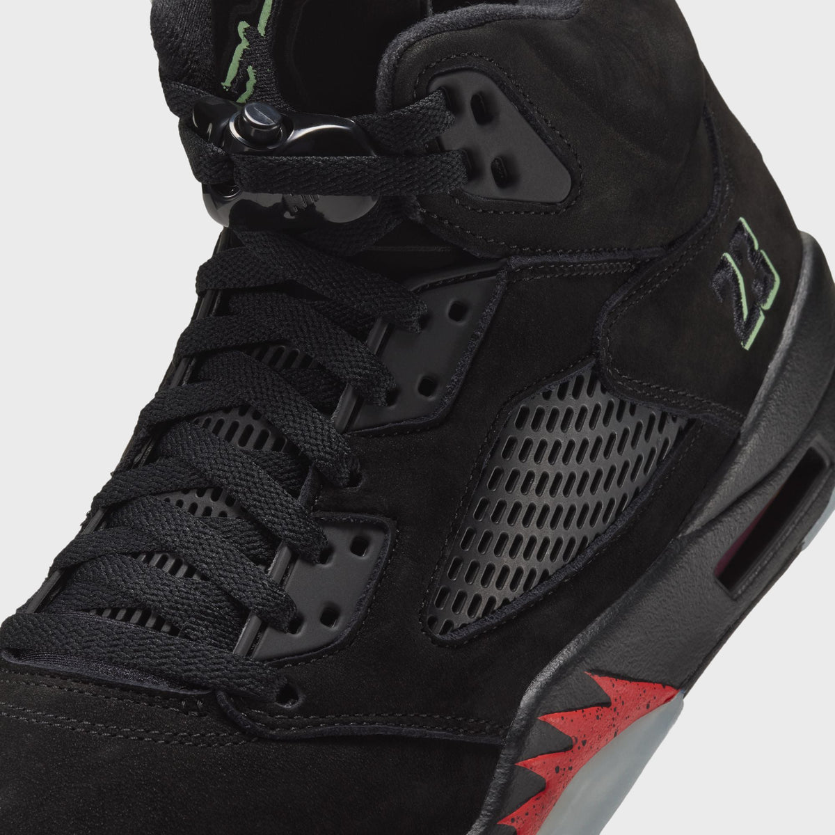 Close-up of Jordan Air Jordan 5 Retro lacing, lace lock and green 23 on black suede with red flame accent