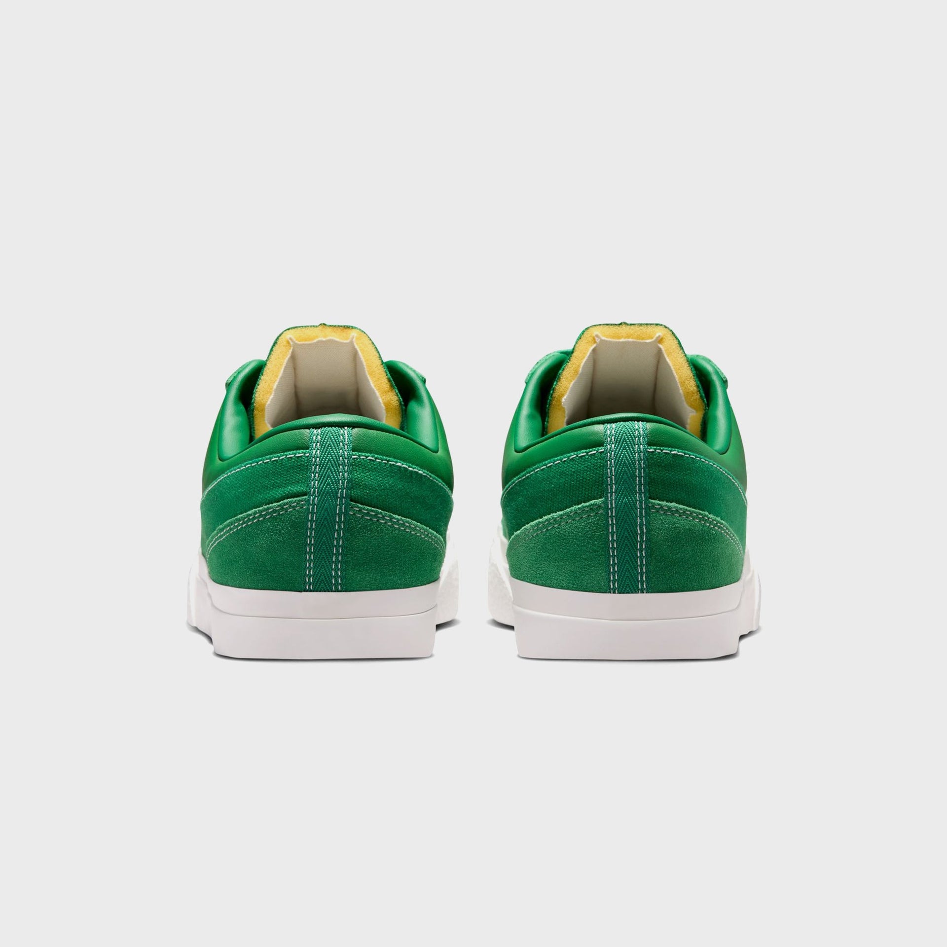 Rear heel view of the Nike Blazy pair in Pine Green with center-seam stitching, yellow collar lining and white sail sole