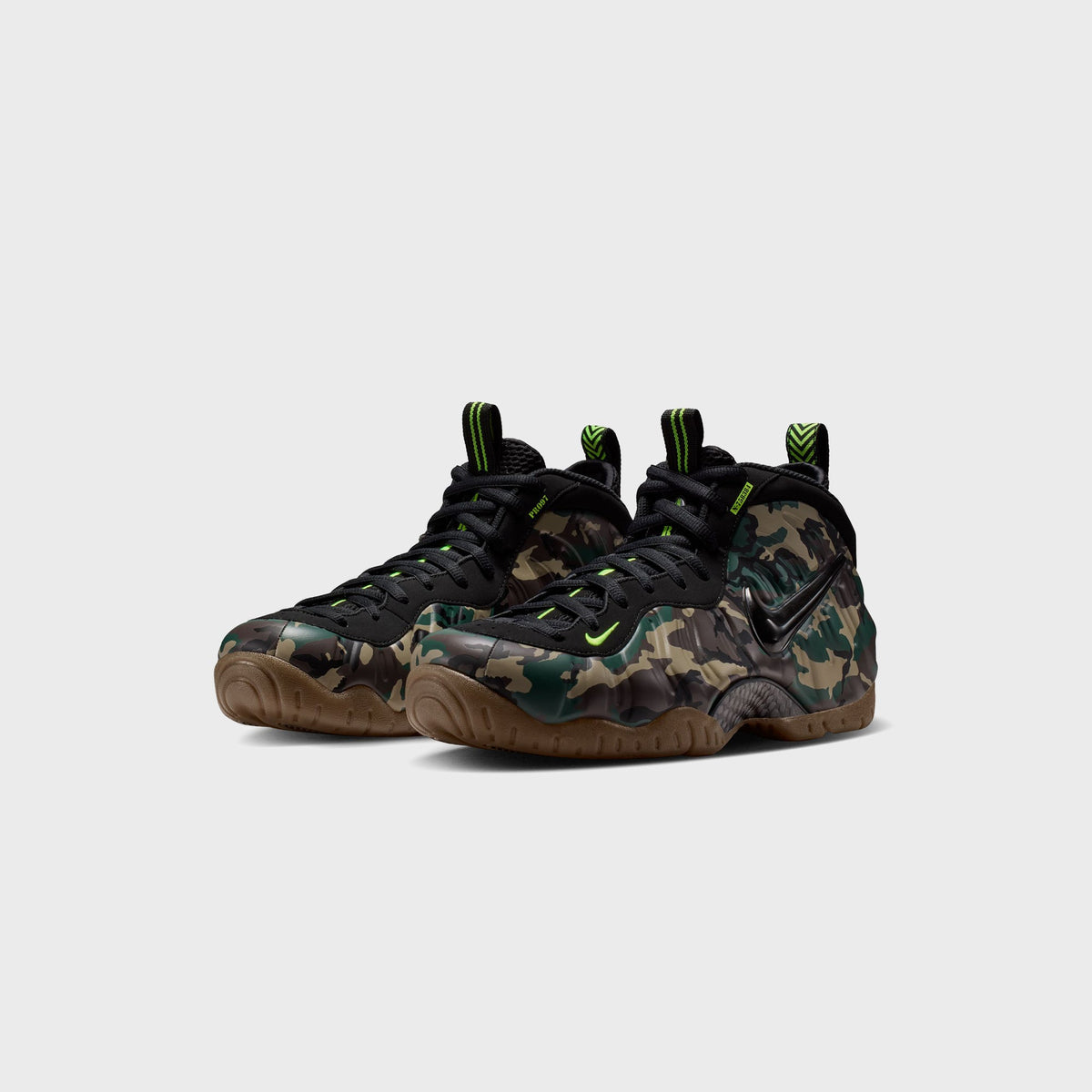 Pair of Nike Air Foamposite Pro sneakers in green camo and black, volt accents, gum soles, three-quarter view