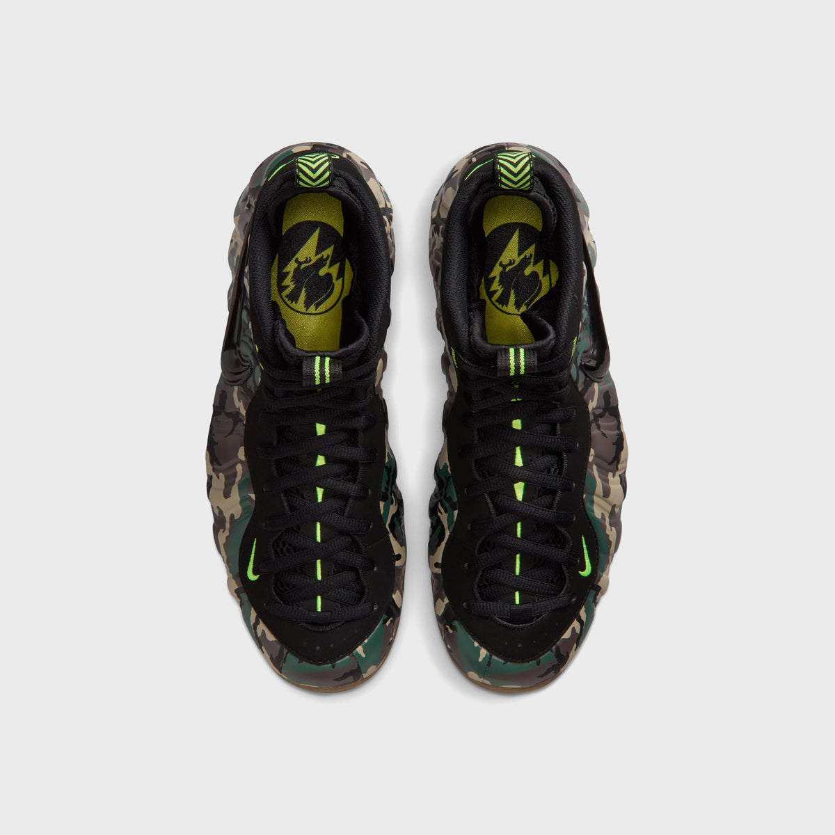Top-down view of Nike Air Foamposite Pro camo sneakers showing black laced upper and volt green pull tabs