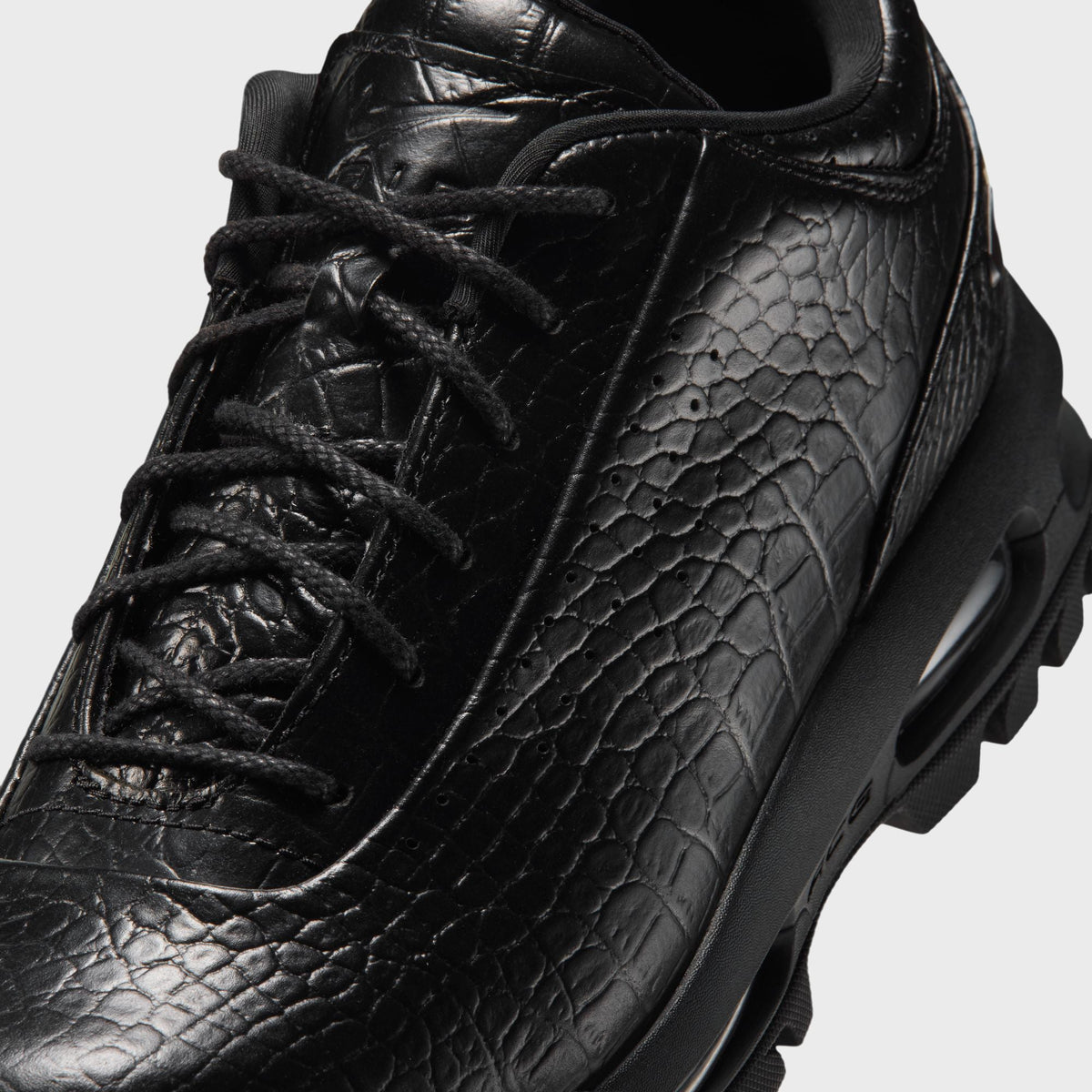 Close-up of Nike Air Max Goadome Low black leather toe box, laces and croc-embossed texture