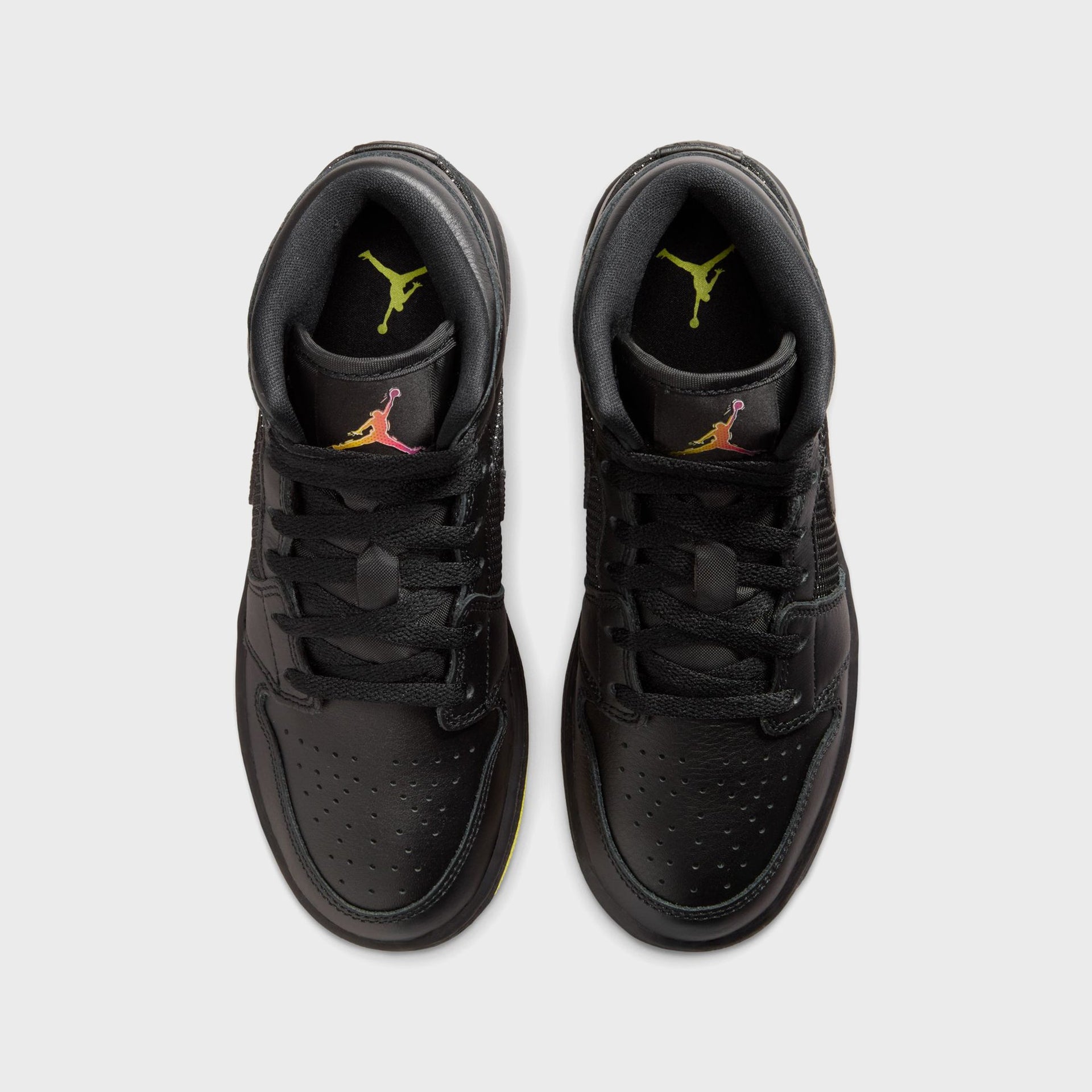 Air Jordan 1 Mid SE pair from above, black perforated toe boxes with yellow Jumpman insoles and gradient tongue logos