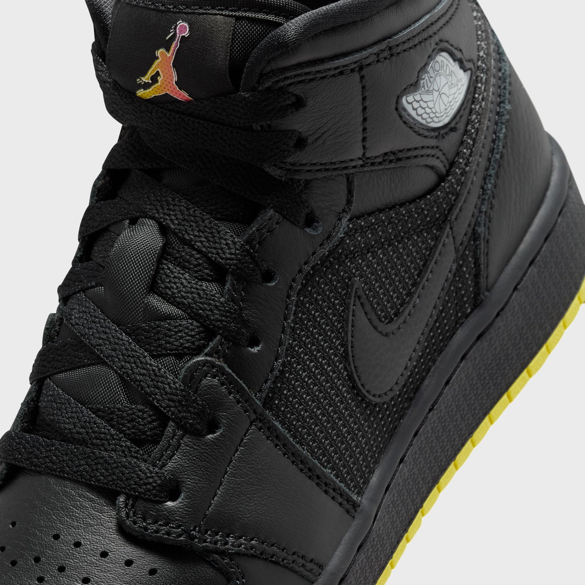 Air Jordan 1 Mid SE close-up of black mesh side panel, black Swoosh, silver Wings logo and gradient Jumpman tongue