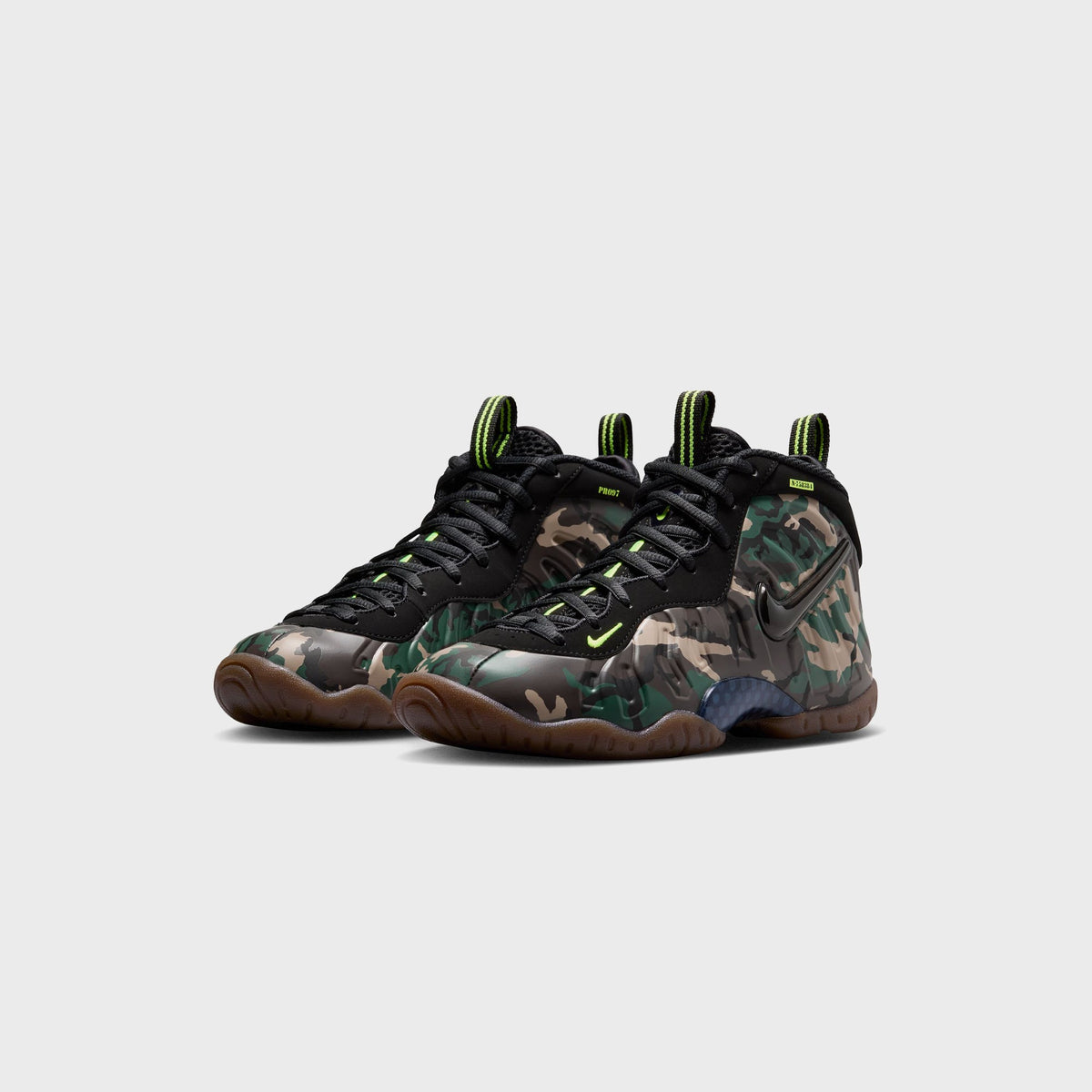 Pair of Nike GS Little Posite Pro sneakers in camo and black with navy heel panel, three-quarter view