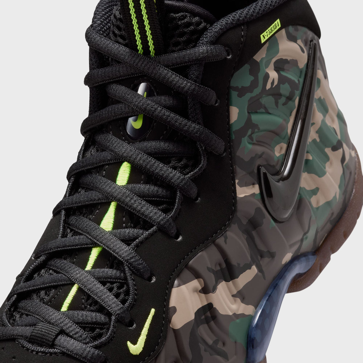 Close-up of Nike GS Little Posite Pro toe featuring glossy black Swoosh on green and tan camo foam