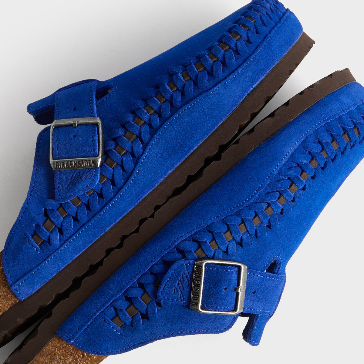 Kith for Birkenstock Boston Braided in Ultra Blue, detail of stacked clogs showing braided welt and Birkenstock x Kith buckles