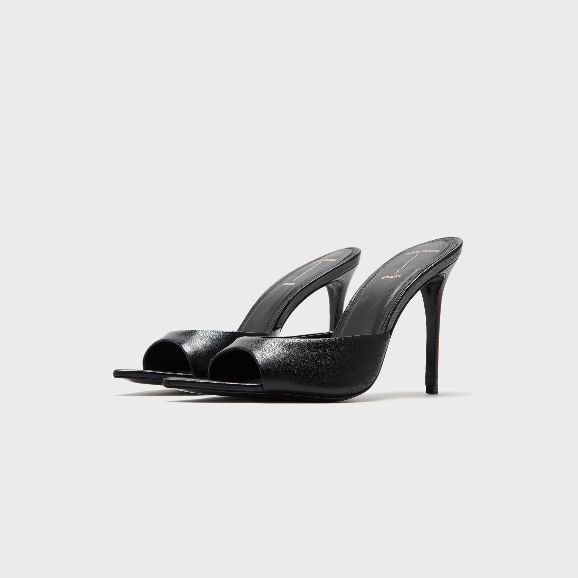 Black Suede Studio Brea heeled mules in black leather, three-quarter front view of the pair