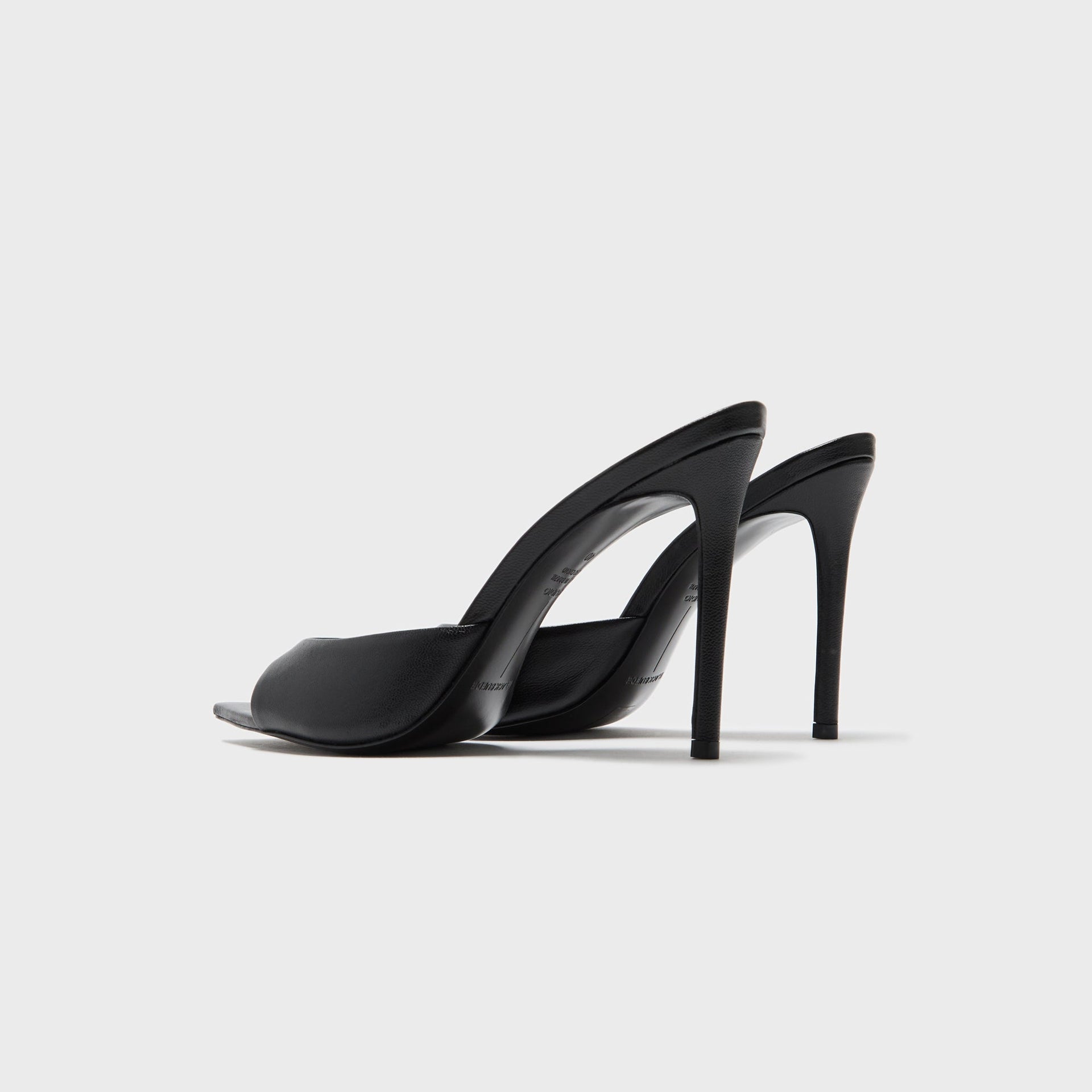 Black Suede Studio Brea heeled mules in black leather, back three-quarter view showing stiletto heels