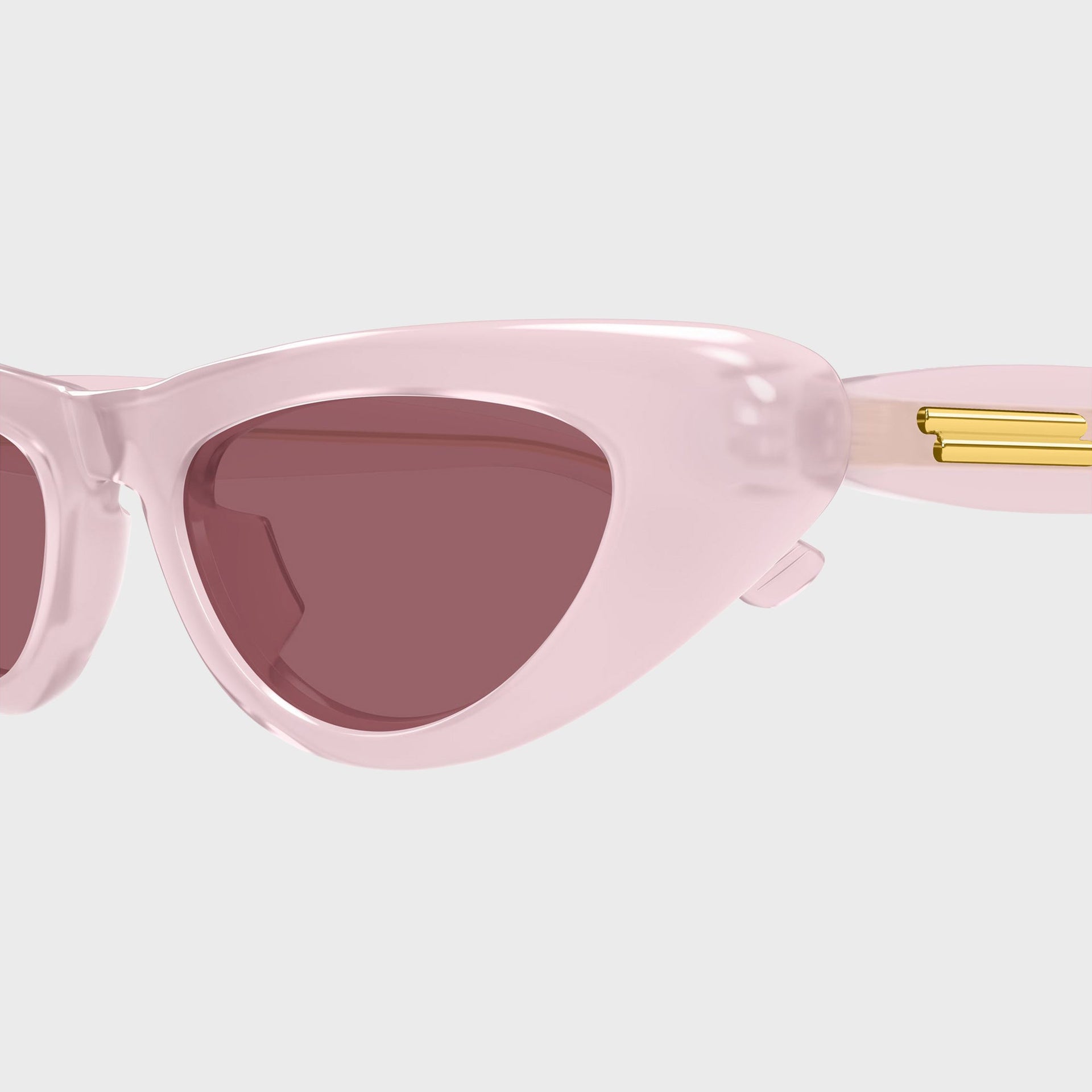 Bottega Veneta Bombe cat-eye sunglasses, close-up of pink frame corner, red lens and gold temple hardware