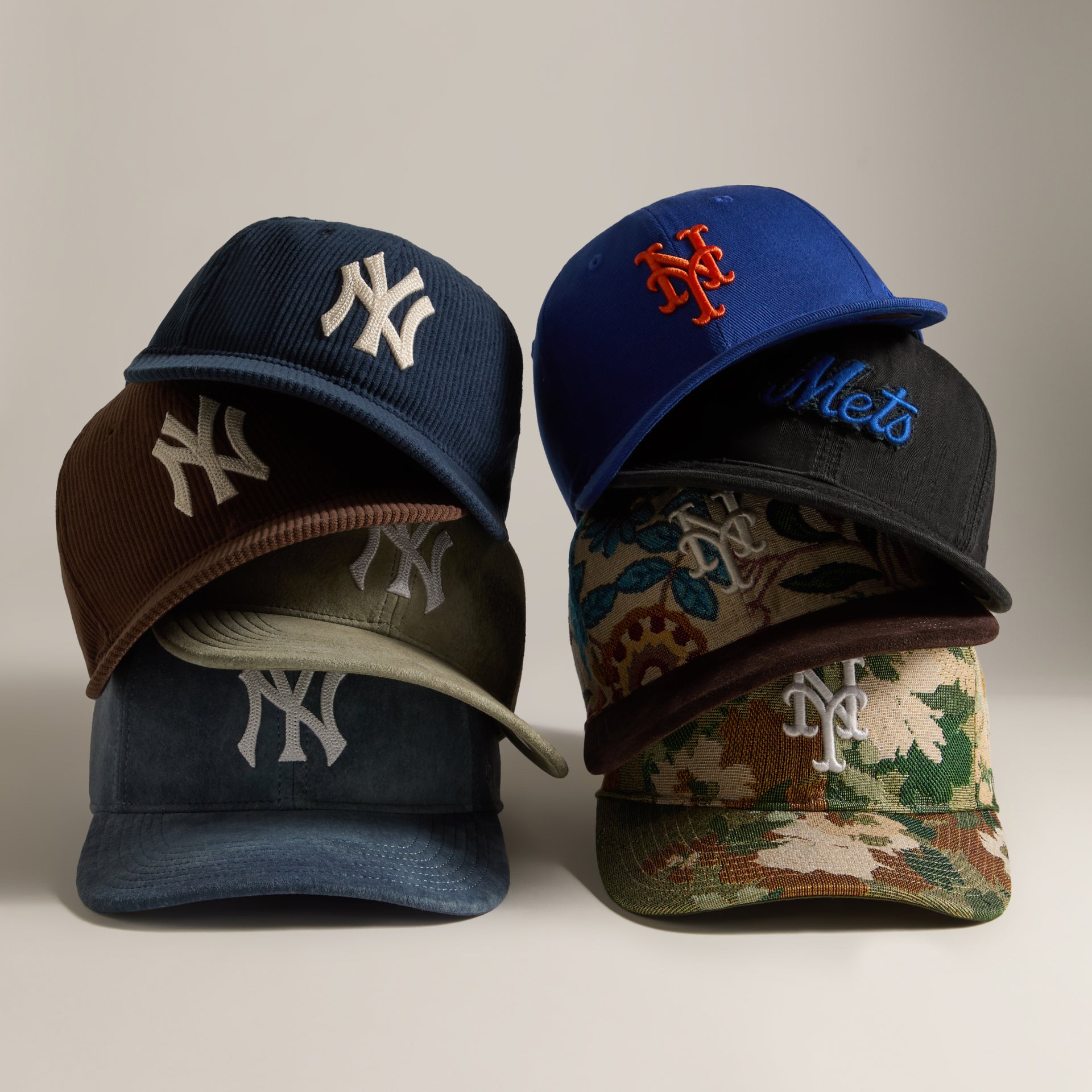 Stack of Kith and MLB baseball caps including navy Yankees and blue Mets snapbacks with camo accents