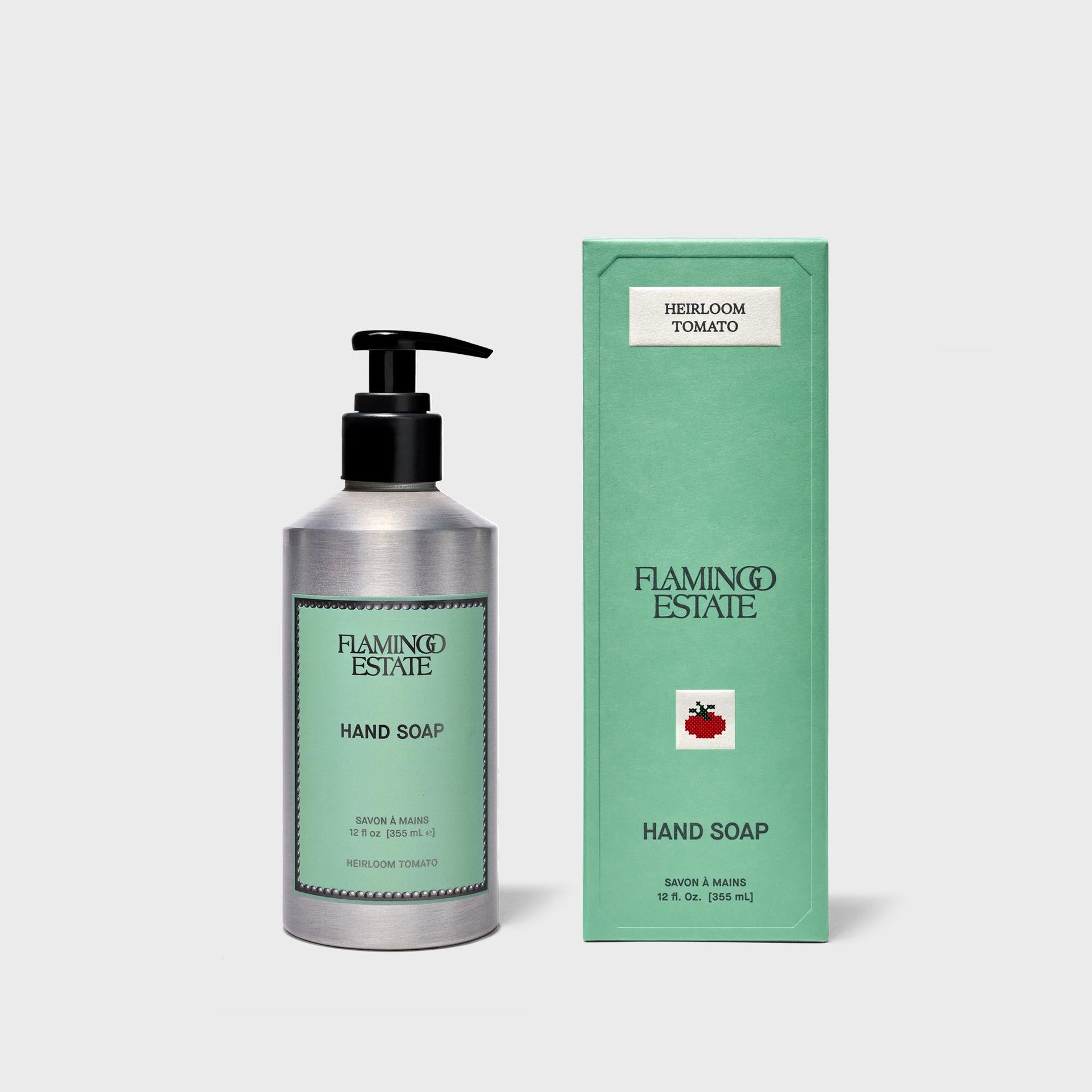 Flamingo Estate Heirloom Tomato hand soap, silver pump bottle beside green box with cross-stitch tomato
