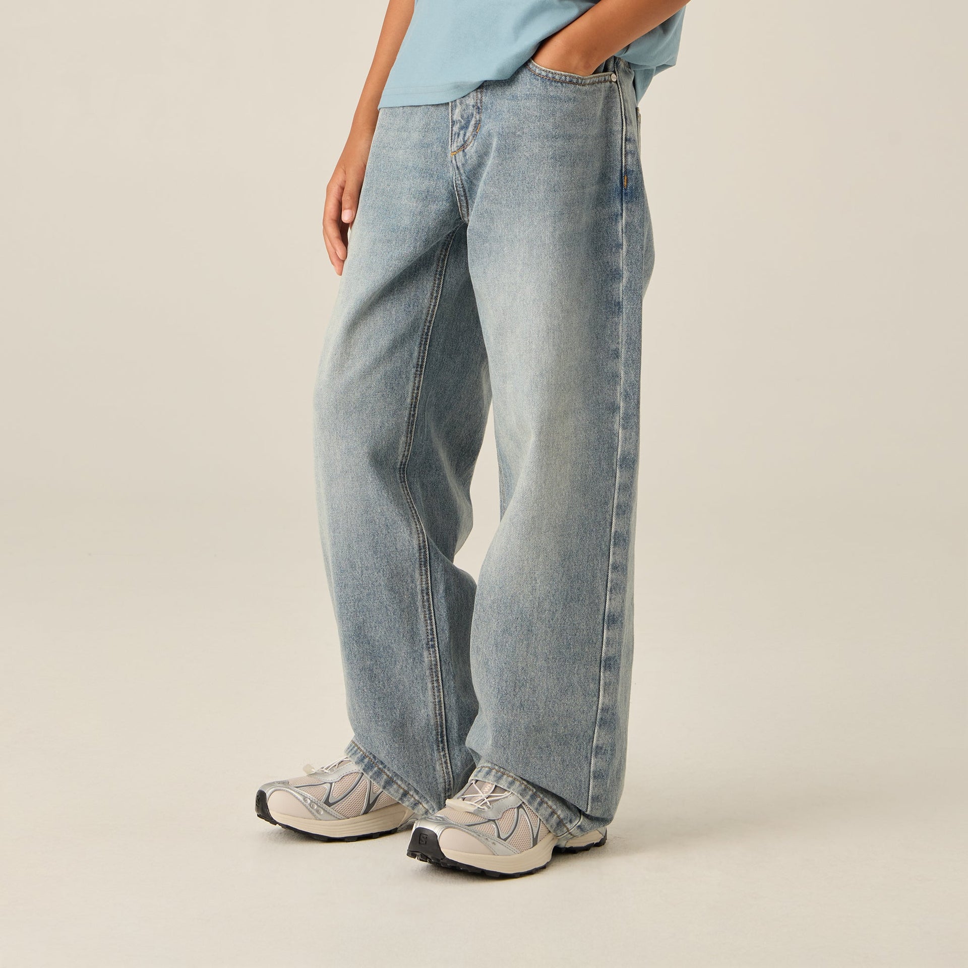 Kith Kids Heston Wide Leg Jean in Roman Wash on model, side view showing relaxed wide leg with silver sneakers