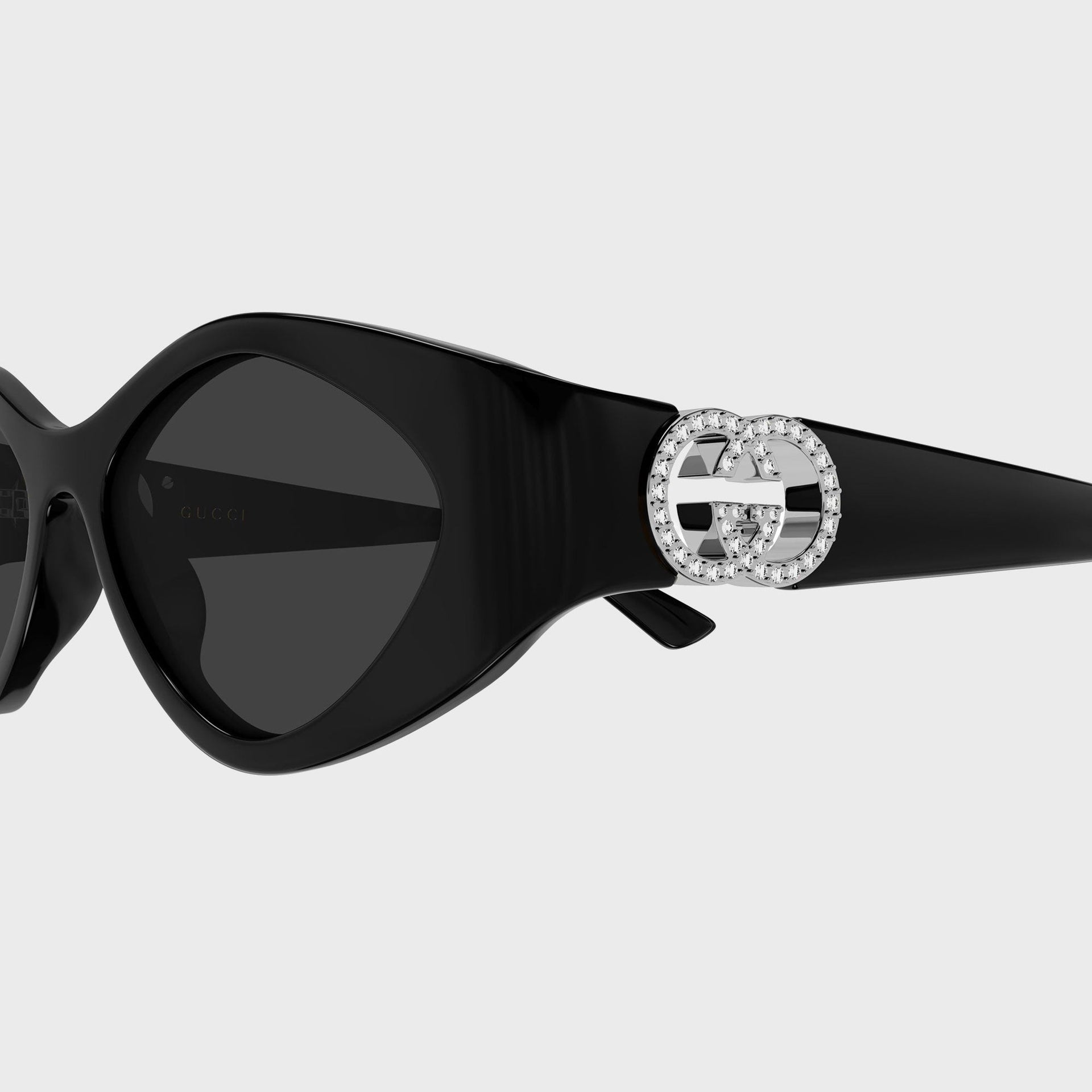 Gucci sunglasses temple detail, crystal-embellished silver interlocking G logo on glossy black arm