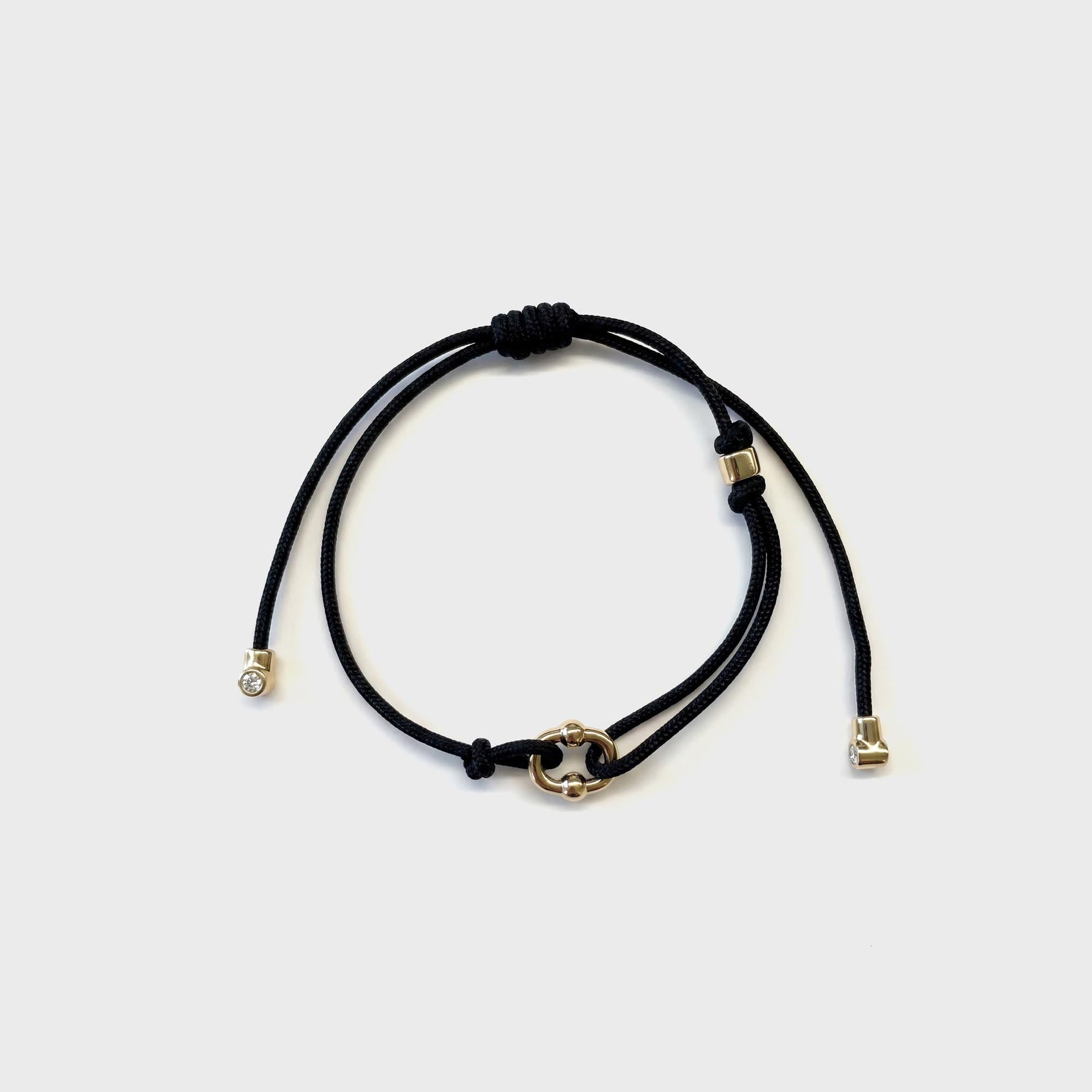 Greg Yuna Umlaut adjustable black cord bracelet with gold interlocking link charm, close view of clasp detail