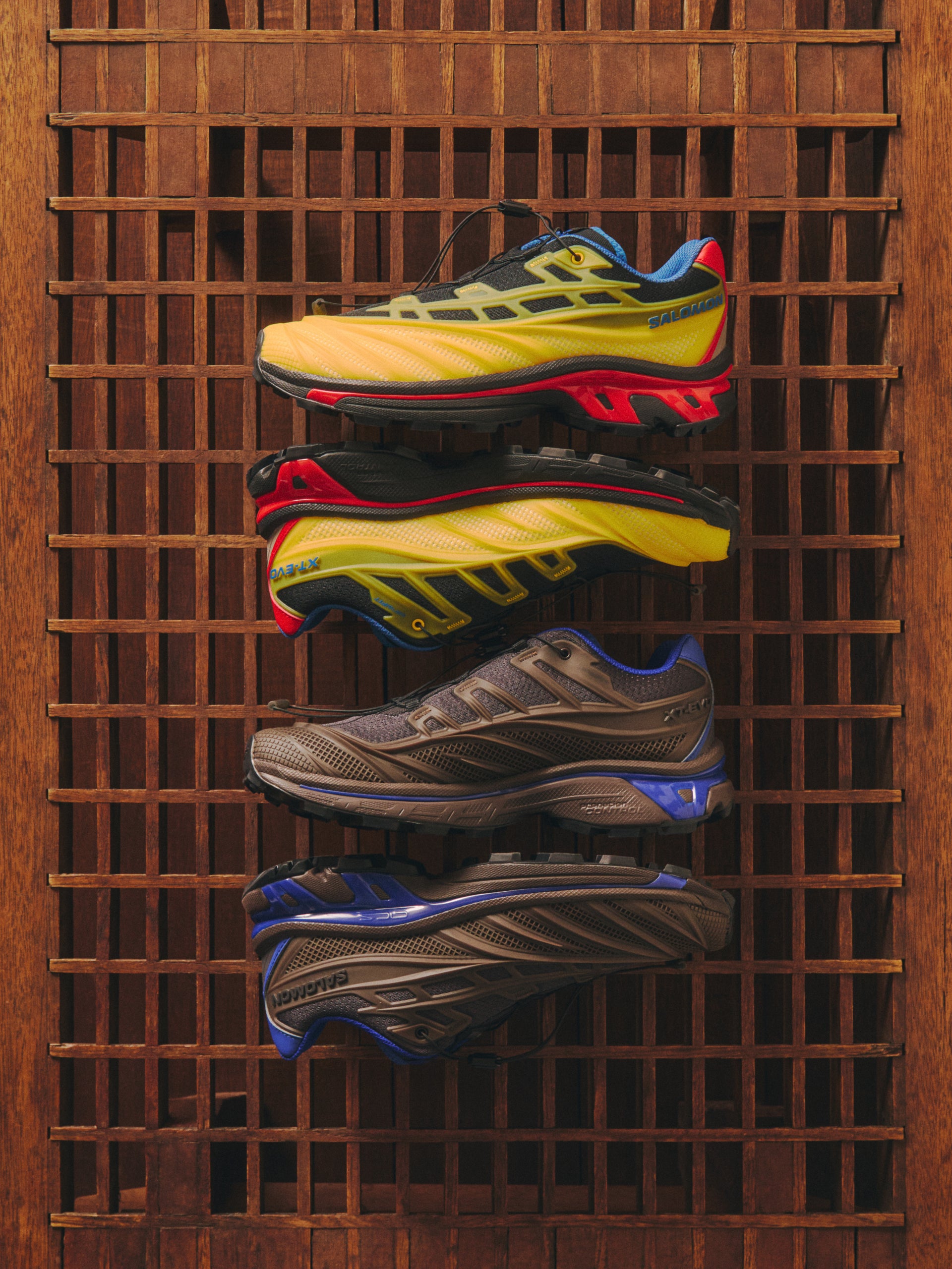 Four Salomon XT-6 sneakers in yellow-red and brown-blue colorways on a wooden lattice screen, side profiles