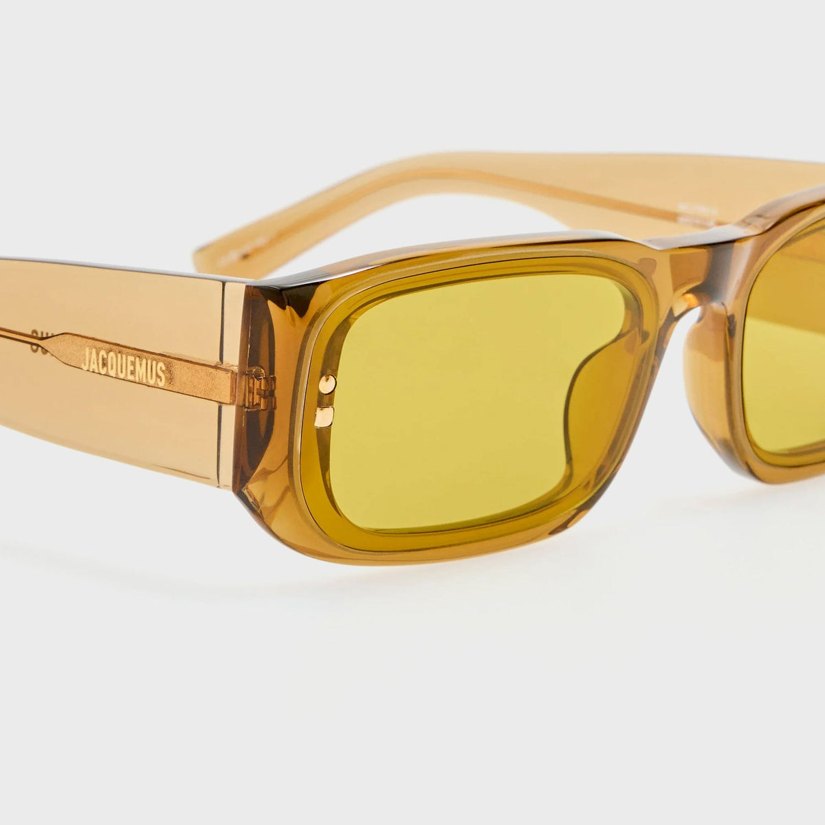 Jacquemus Pisco sunglasses in translucent amber, close-up angled view showing the temple arm