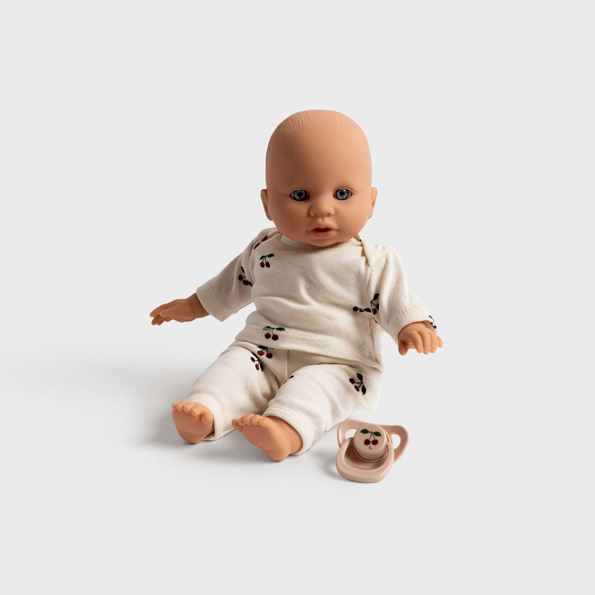 Konges Sløjd Elli the Doll in Multi, doll seated on the floor beside its pacifier