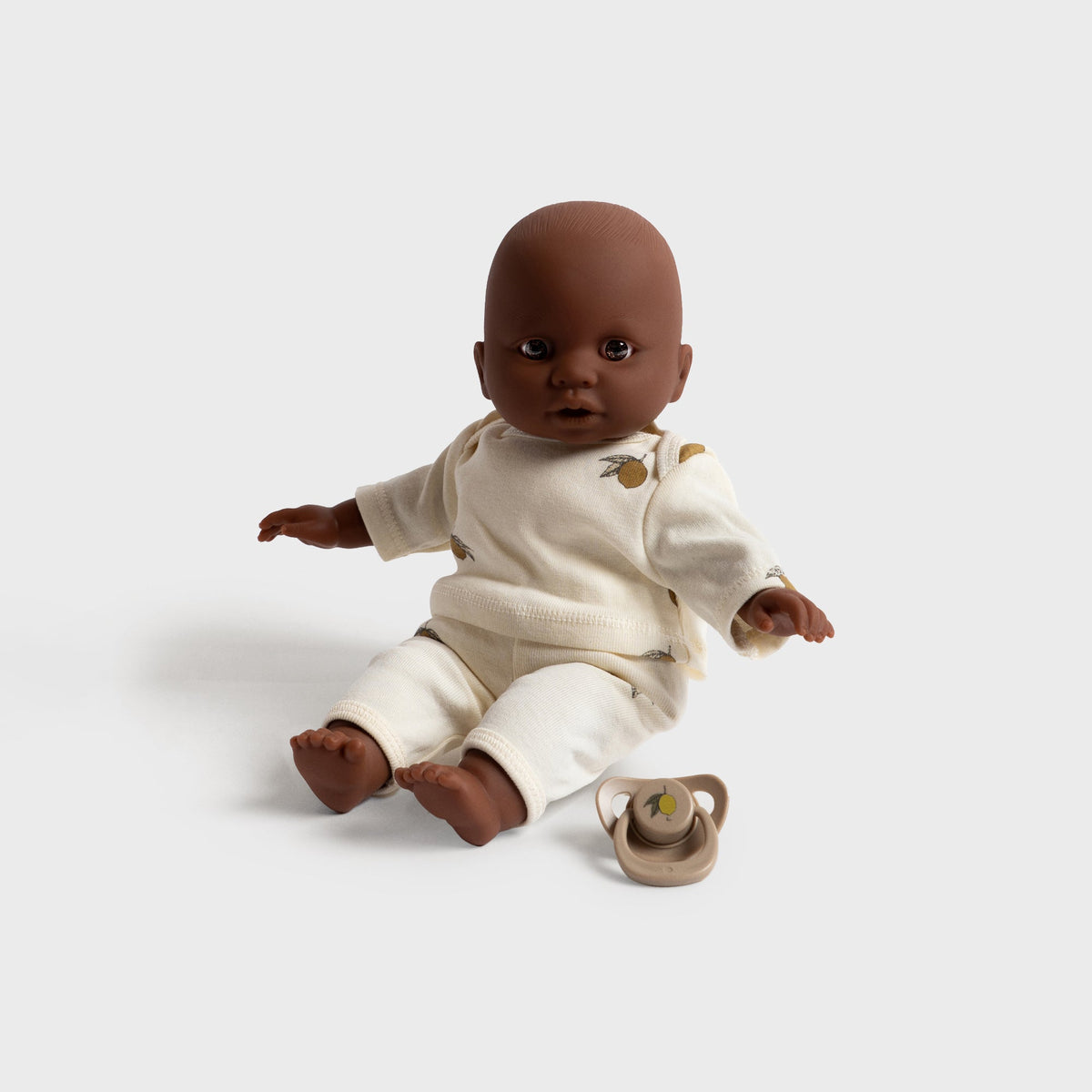 Konges Sløjd Billie the Doll in Multi, doll seated on the floor beside its pacifier