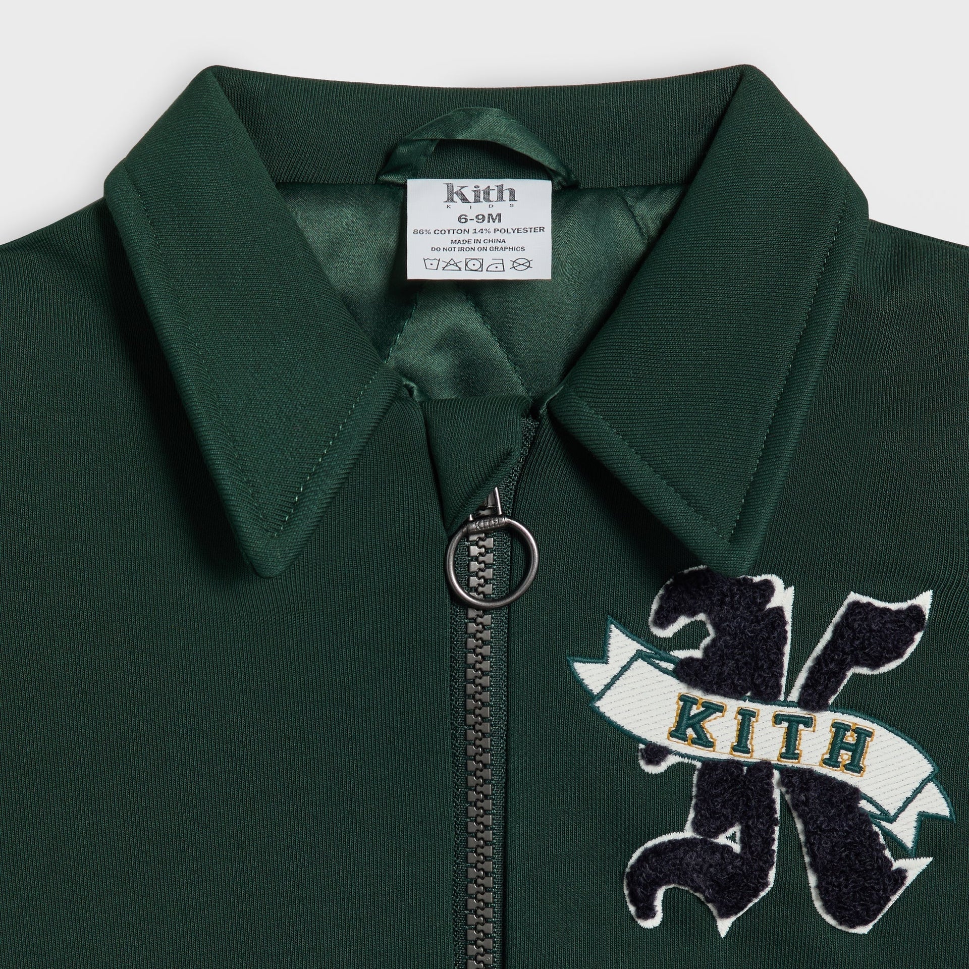 Close-up of the Kith Baby Varsity Jacket's collar, zipper pull and embroidered K Kith crest patch